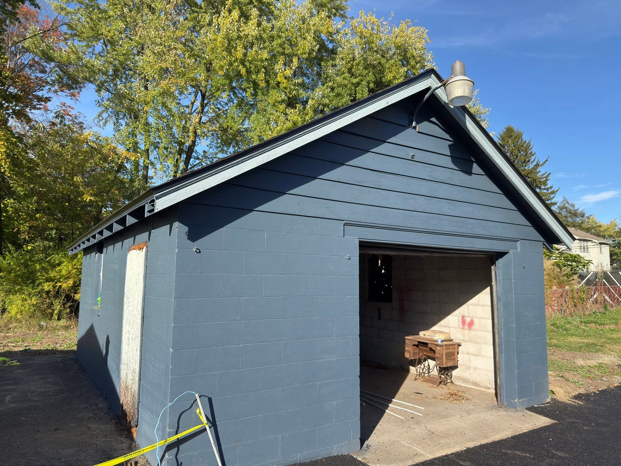 A blue block garage with its fascia and rake boards painted, under a shingle roof