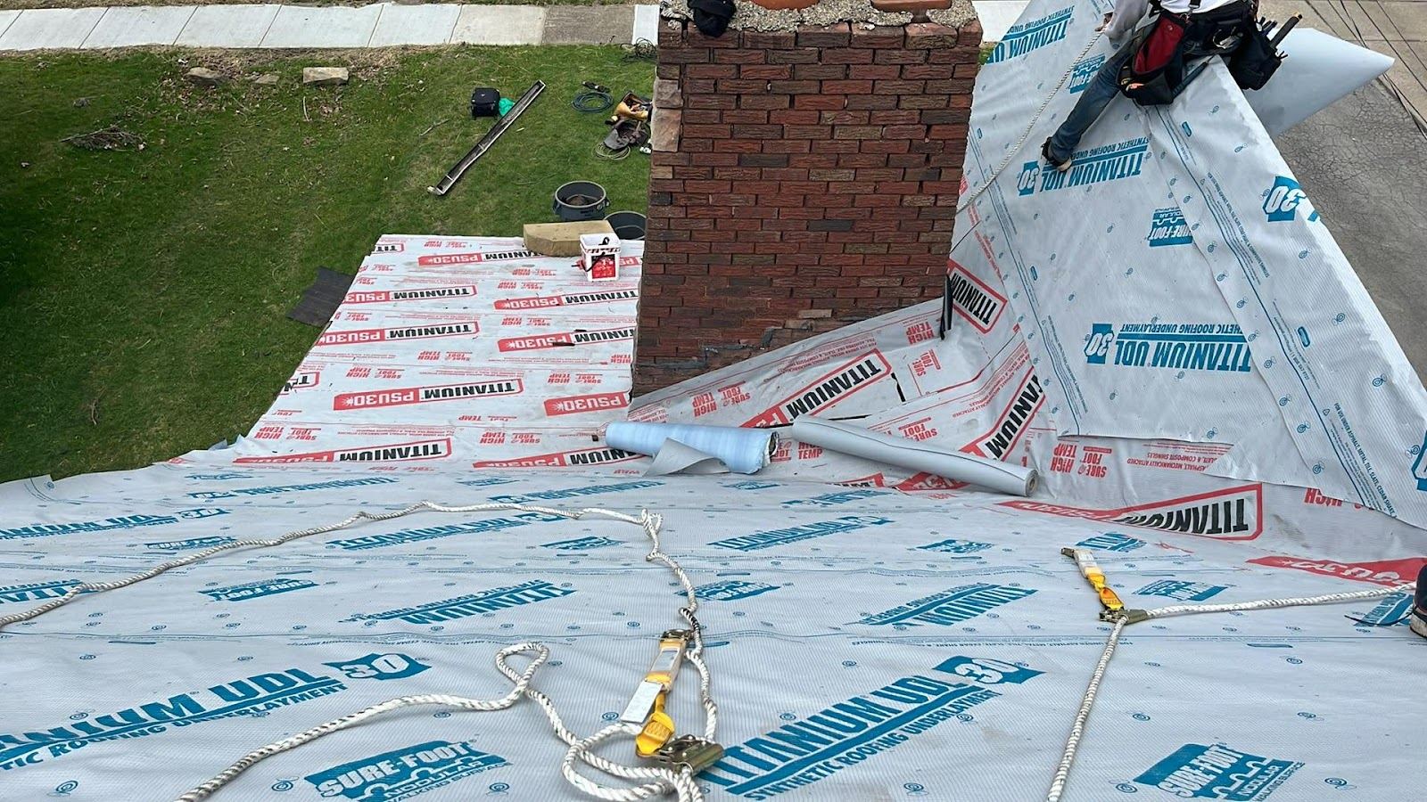 New synthetic underlayment laid around a brick chimney before the shingles go on