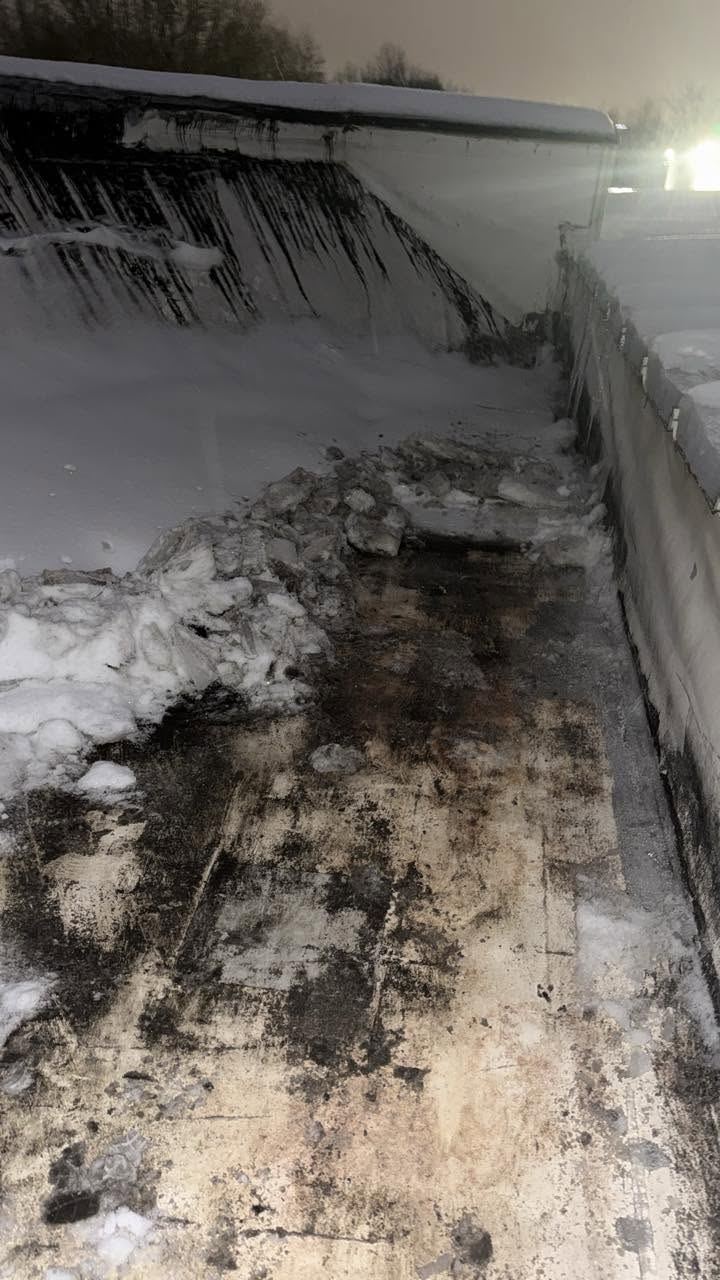 Snow cleared along the wall of a flat roof at night, the roof surface showing