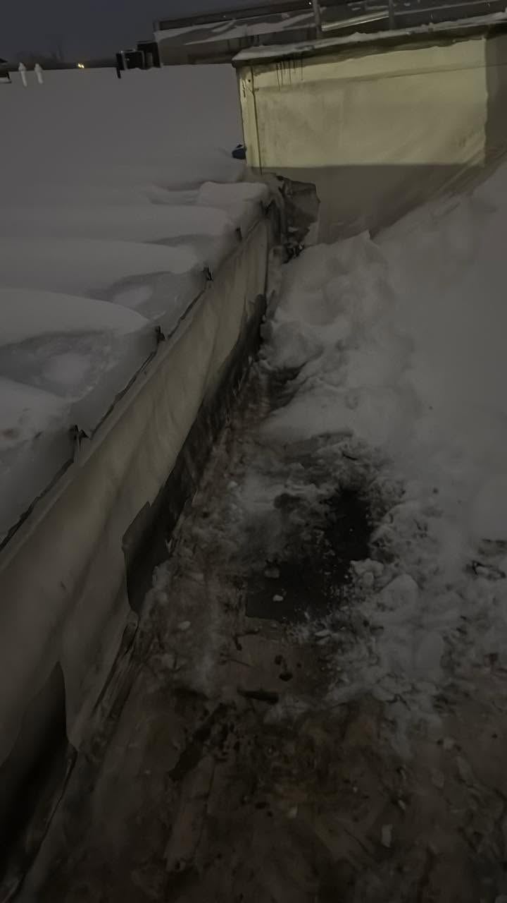 Snow dug out beside a wall on a flat roof at night