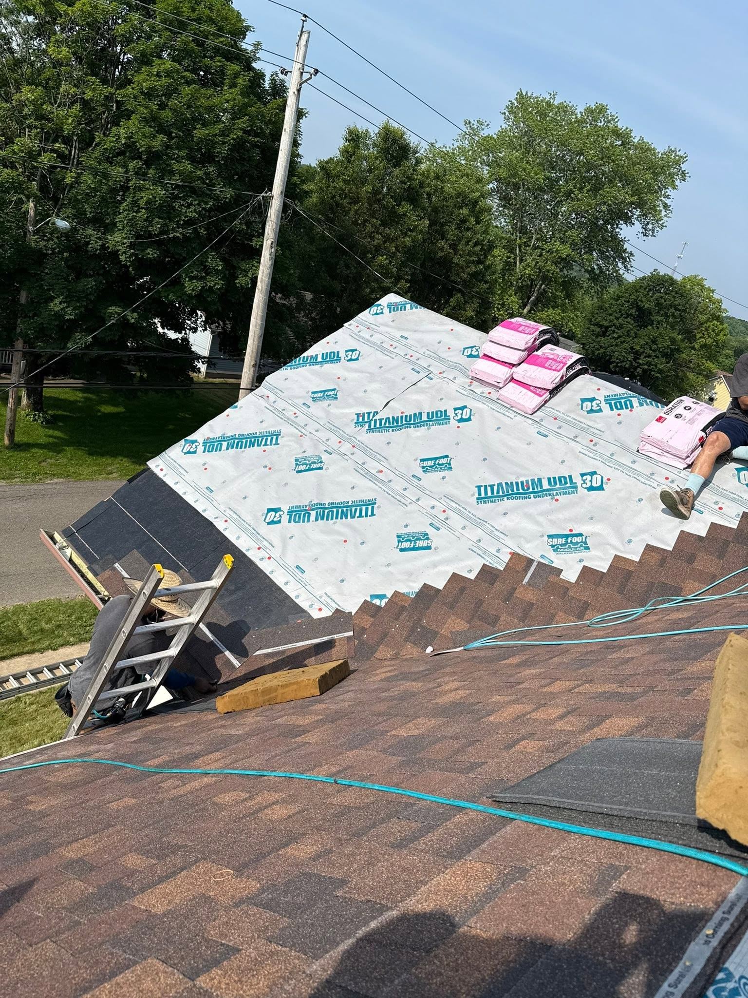 Underlayment down, a ladder up and shingle bundles ready on a roof
