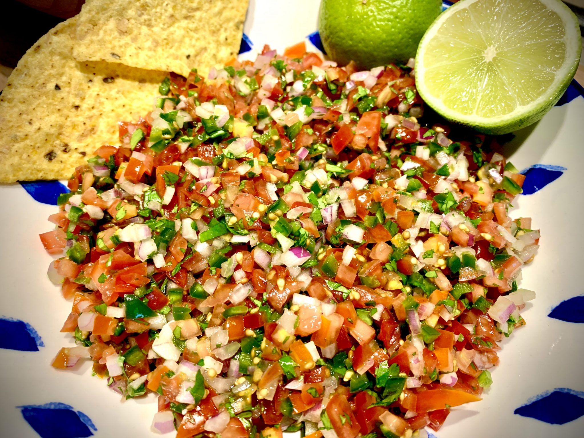 Pico de gallo next to some chips and halved limes