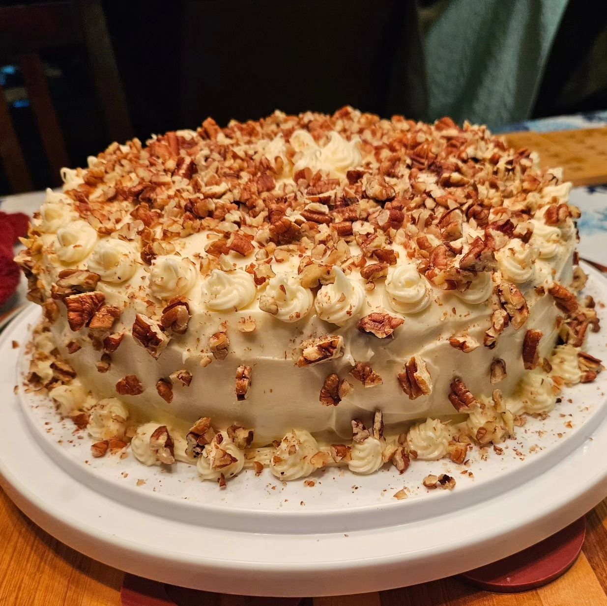 carrot cake covered in frosting and chopped pecans