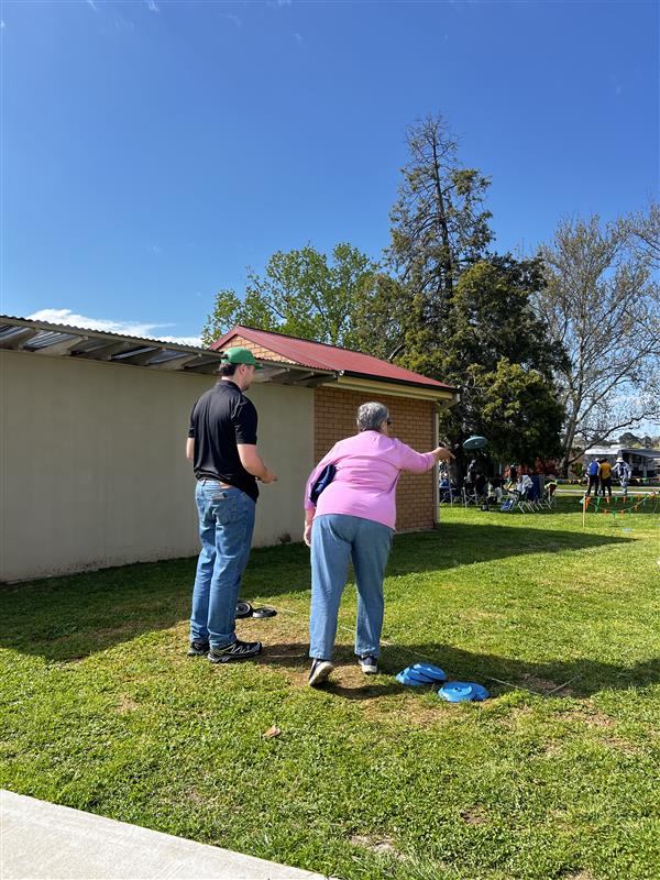 group of people standing on grass playing a game like lawn bowls with discs