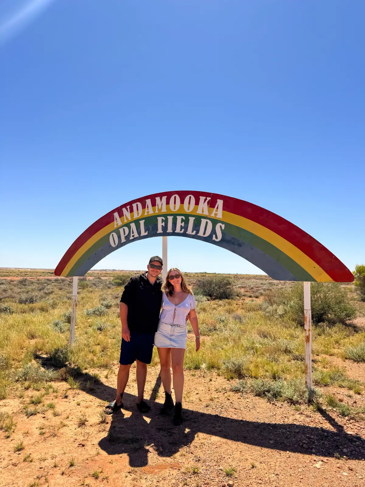 2 people posed in front of the Andamooka Opal Fields sign