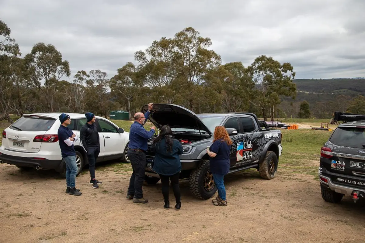 A group of people standing next to a car Description automatically generated