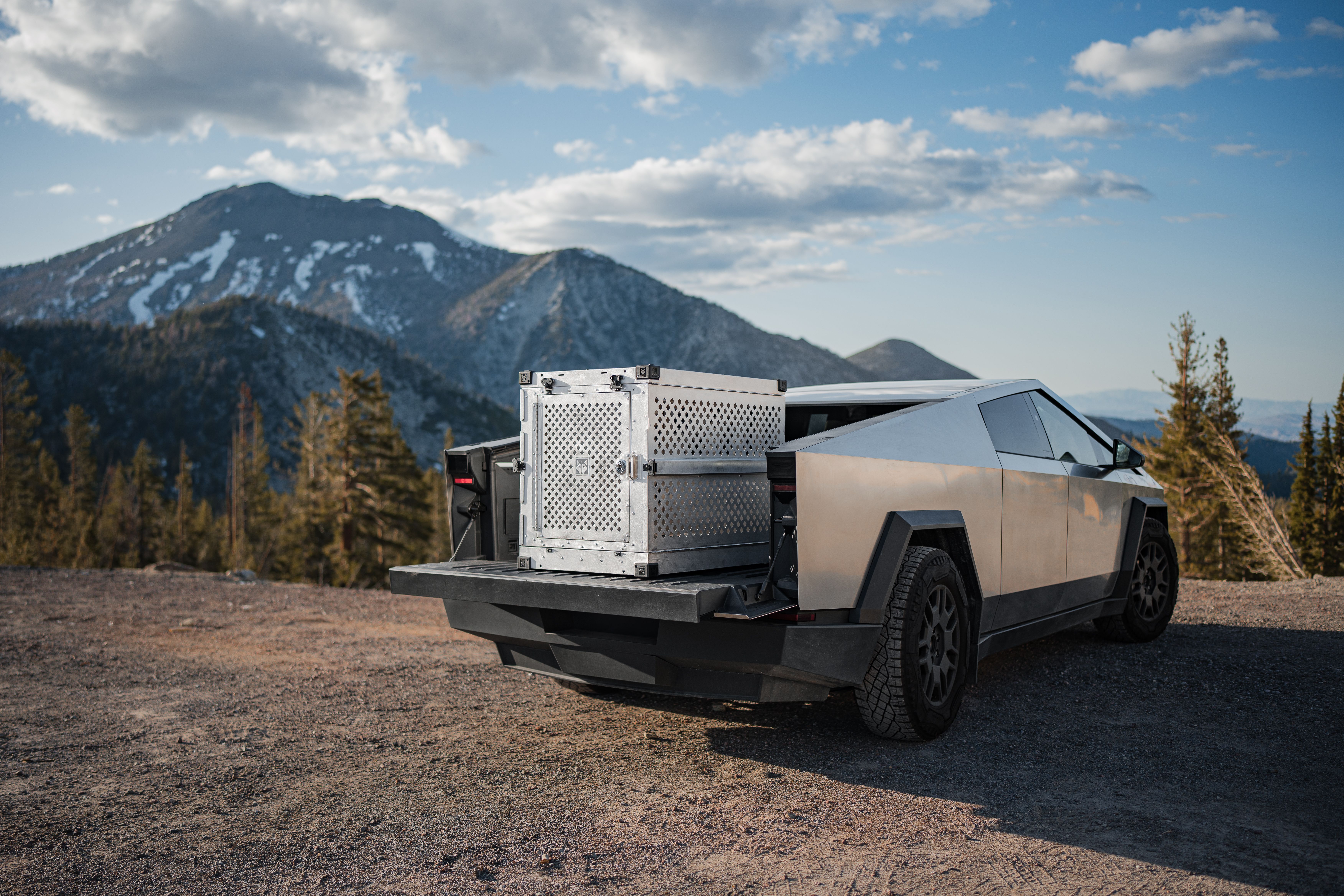 A Tesla Cybertruck with its tray open in a mountainous environment