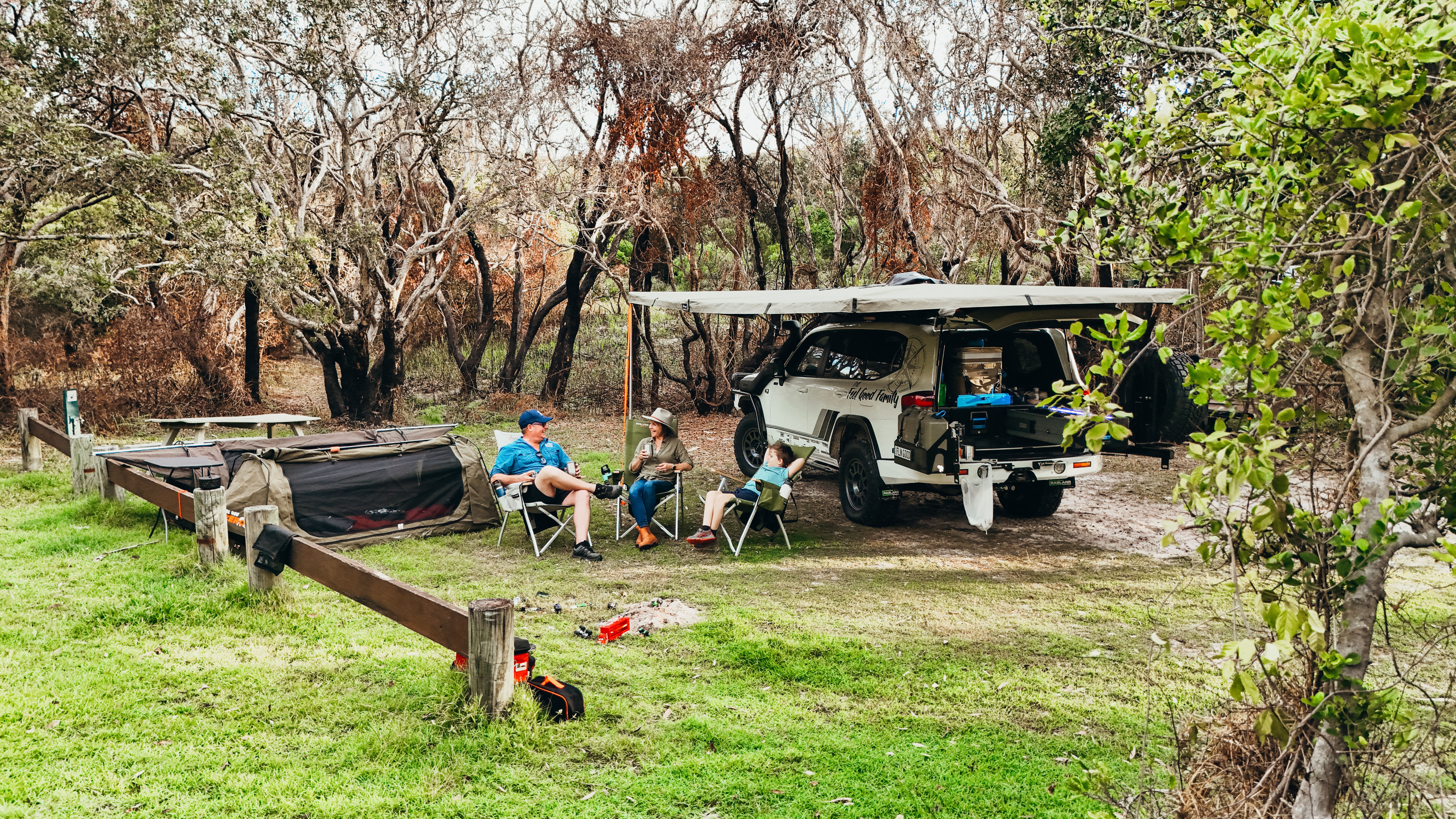 a family and their 4x4 camped under trees