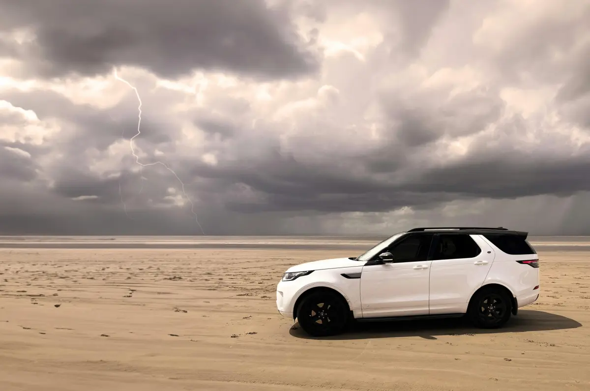 white 4x4 on beach with stormy sky
