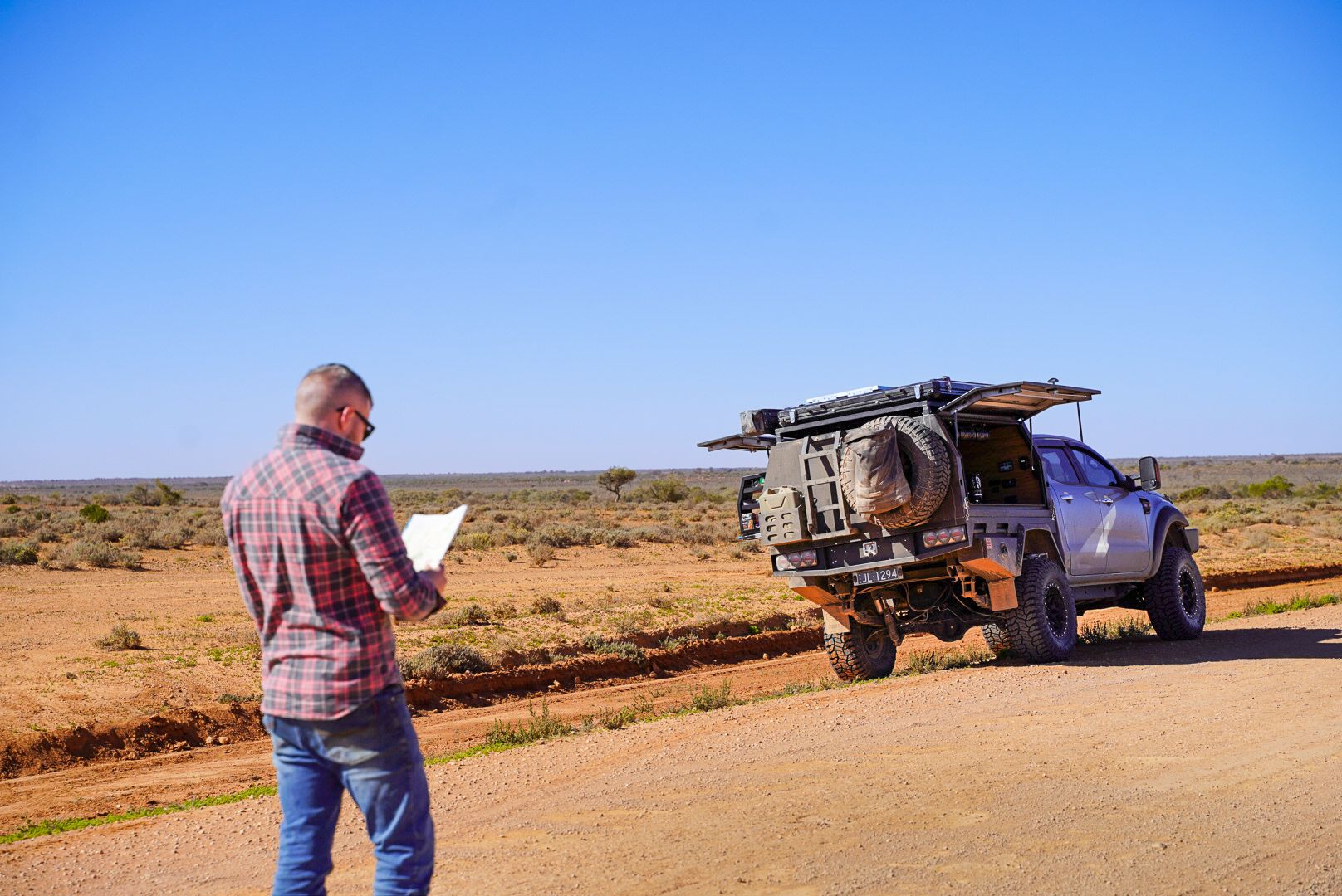 man standing with a 4wd in the outback looking at a piece of paper