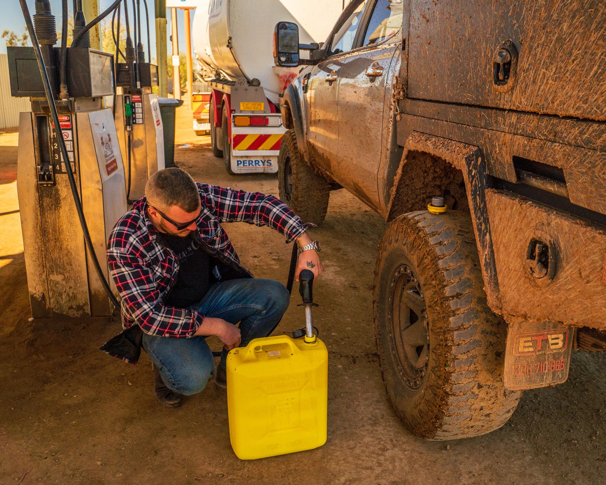 Josh from Adventure Intel Australia filling up a jerry can at a service station in the Outback