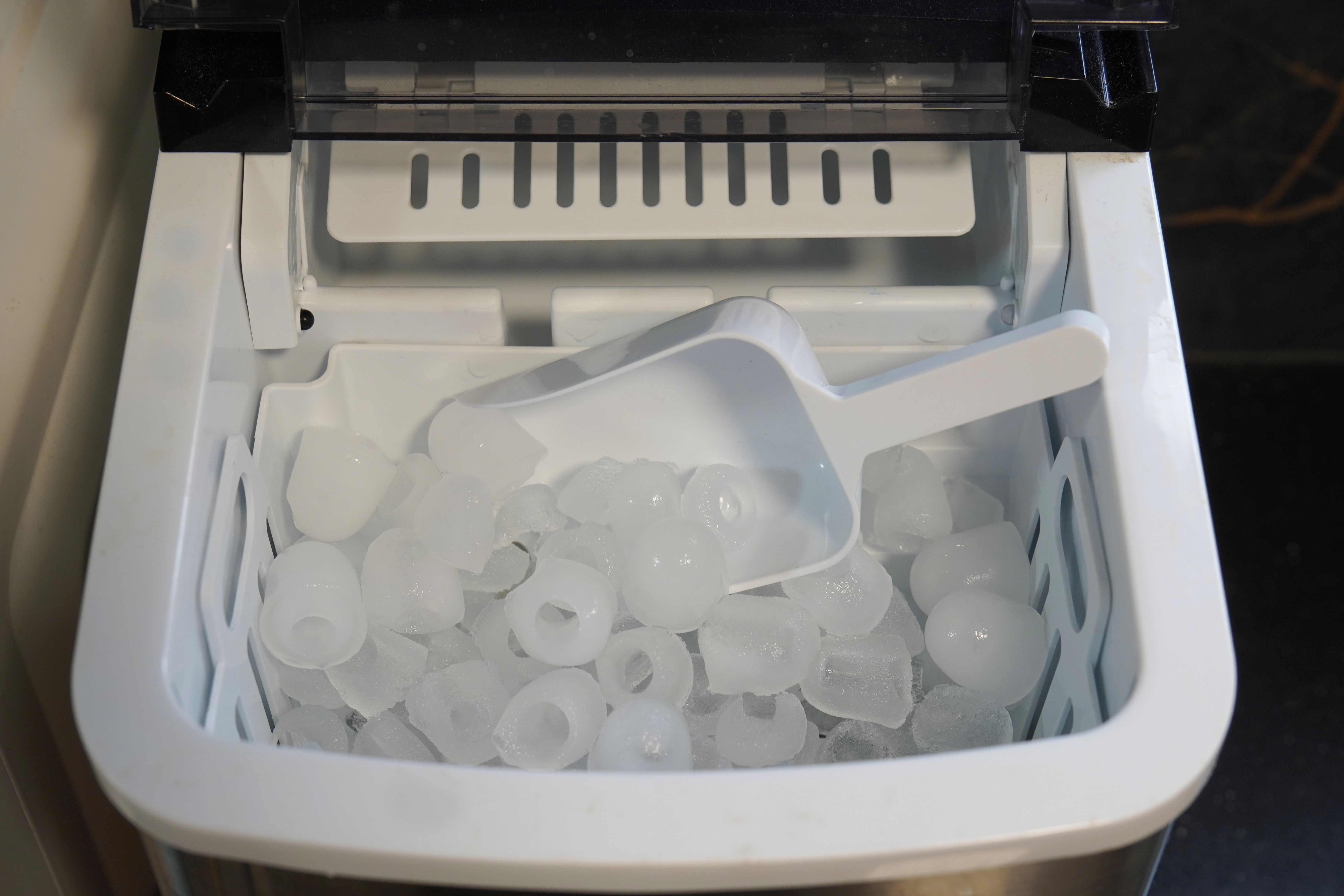 domestic ice maker full of ice with a scoop