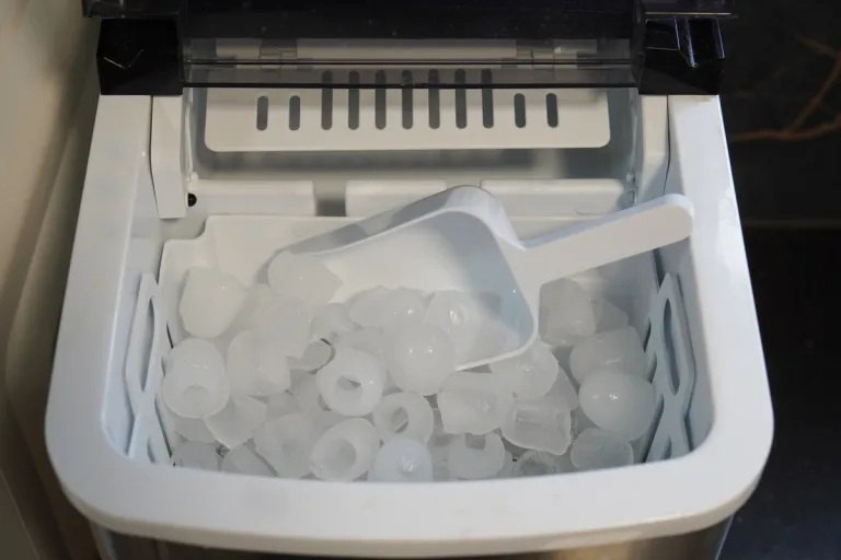 domestic ice maker full of ice with a scoop
