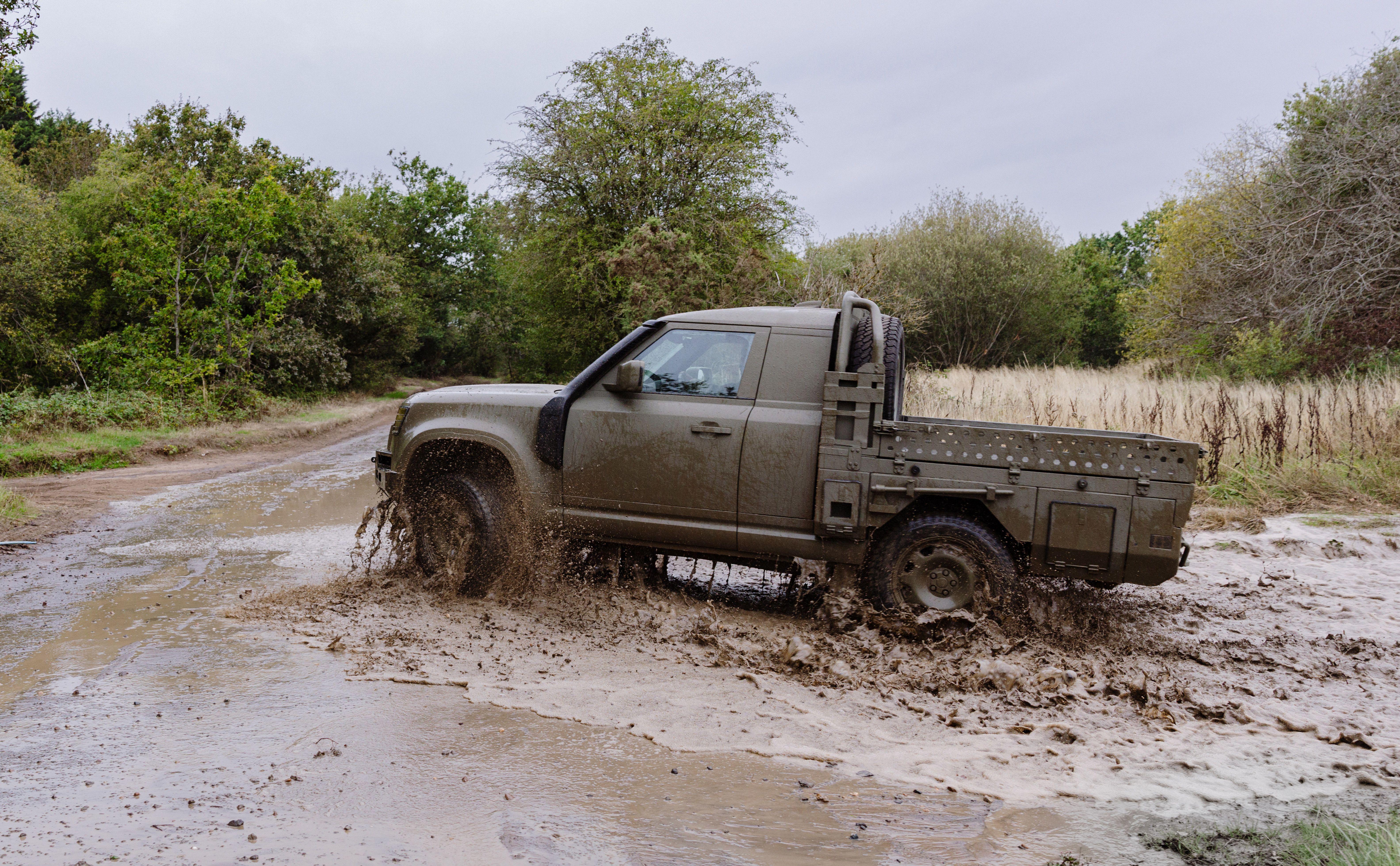 A Land Rover Defender Wolf Series II ute being driven through mud in the UK