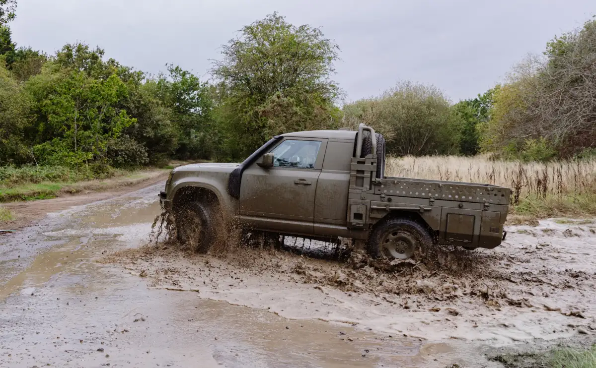 A Land Rover Defender Wolf Series II ute being driven through mud in the UK