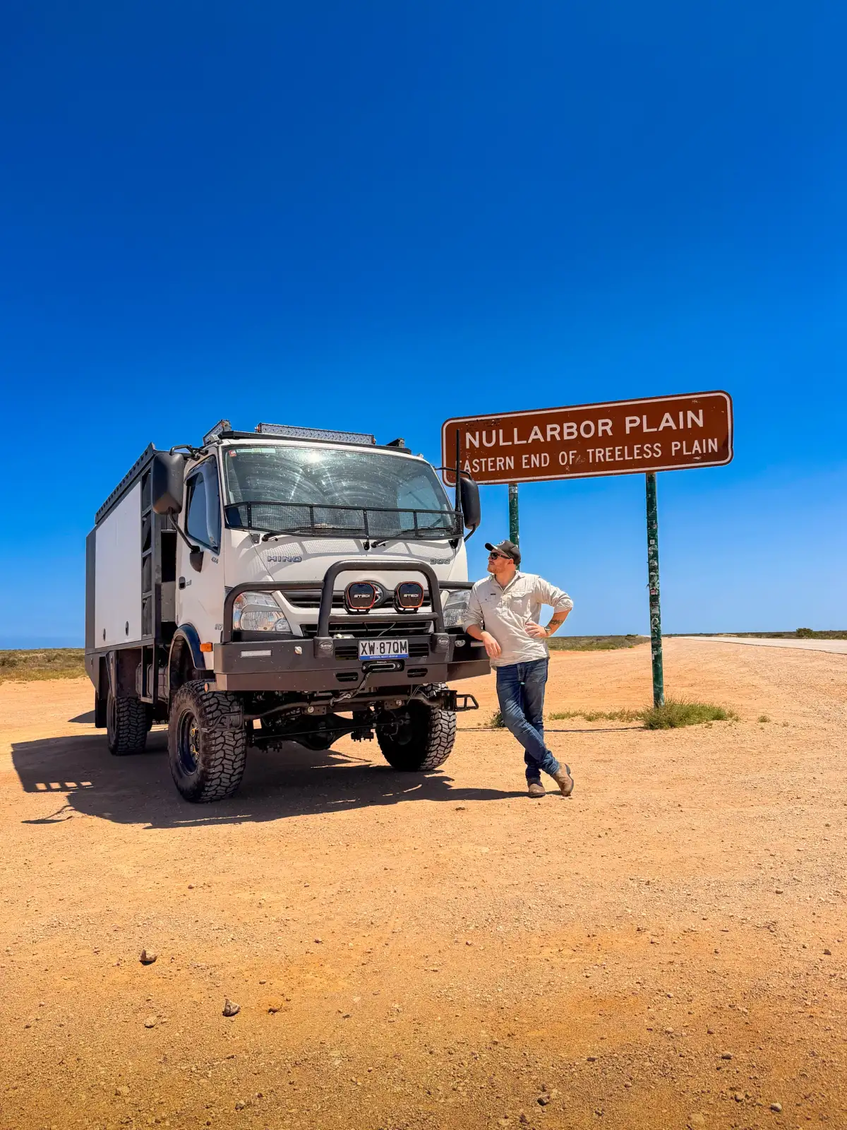 A 4X4 truck and its driver posed next to a road sign