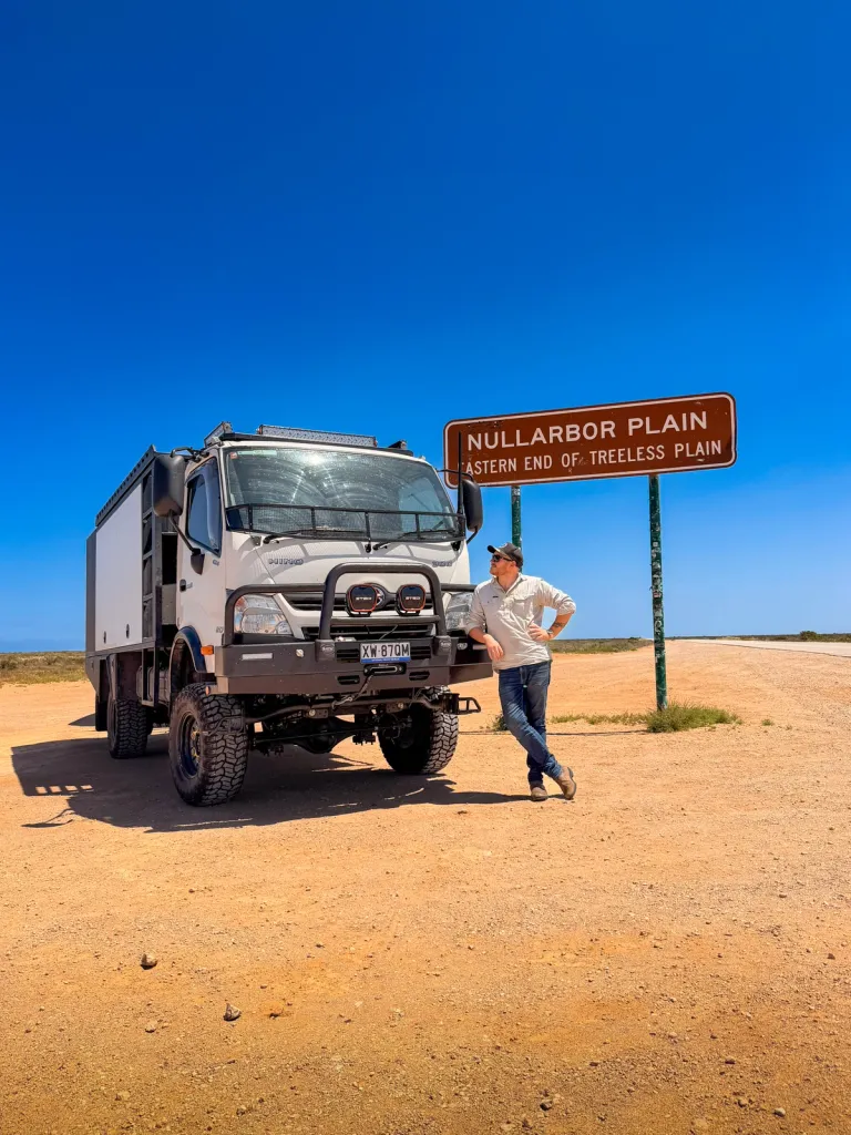 A 4X4 truck and its driver posed next to a road sign