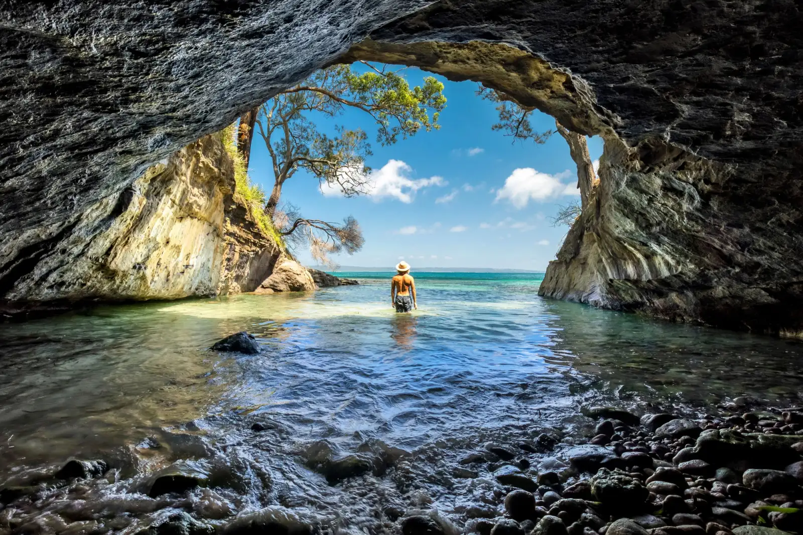 Man enjoying the sun from a sea cave near Murrays Beach, Jervis Bay in Booderee National Park.