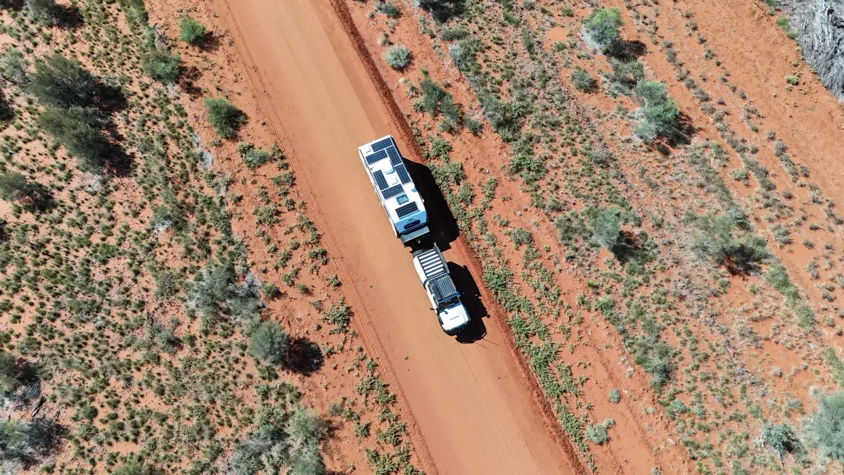 aerial shot of 4x4 towing caravan through red dusty road