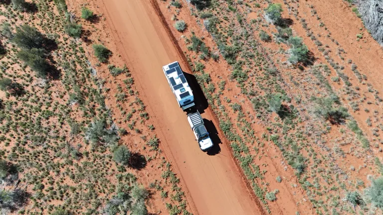 aerial shot of 4x4 towing caravan through red dusty road