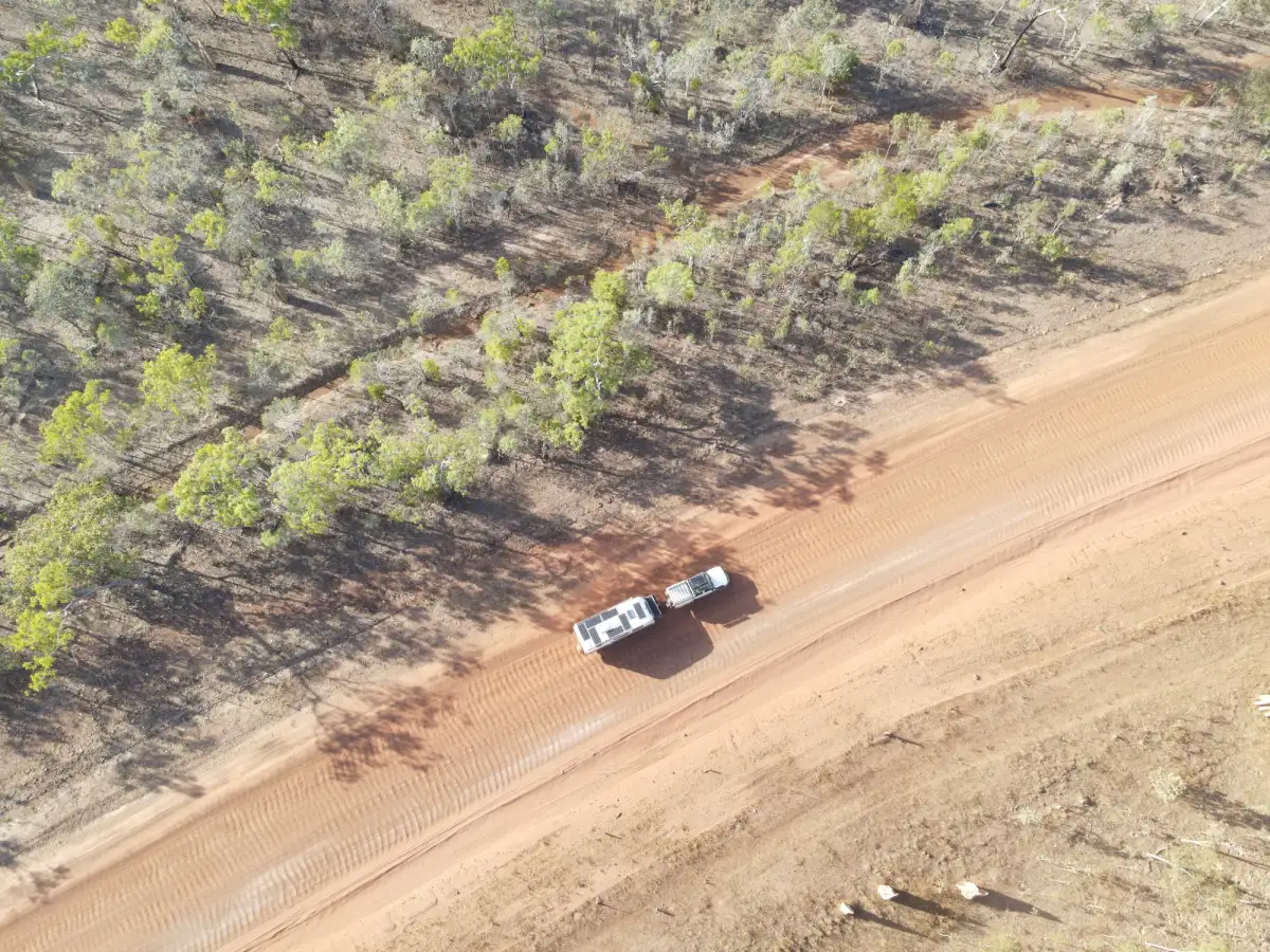 A white Toyota LandCruiser 4X4 towing a caravan on a dirt road