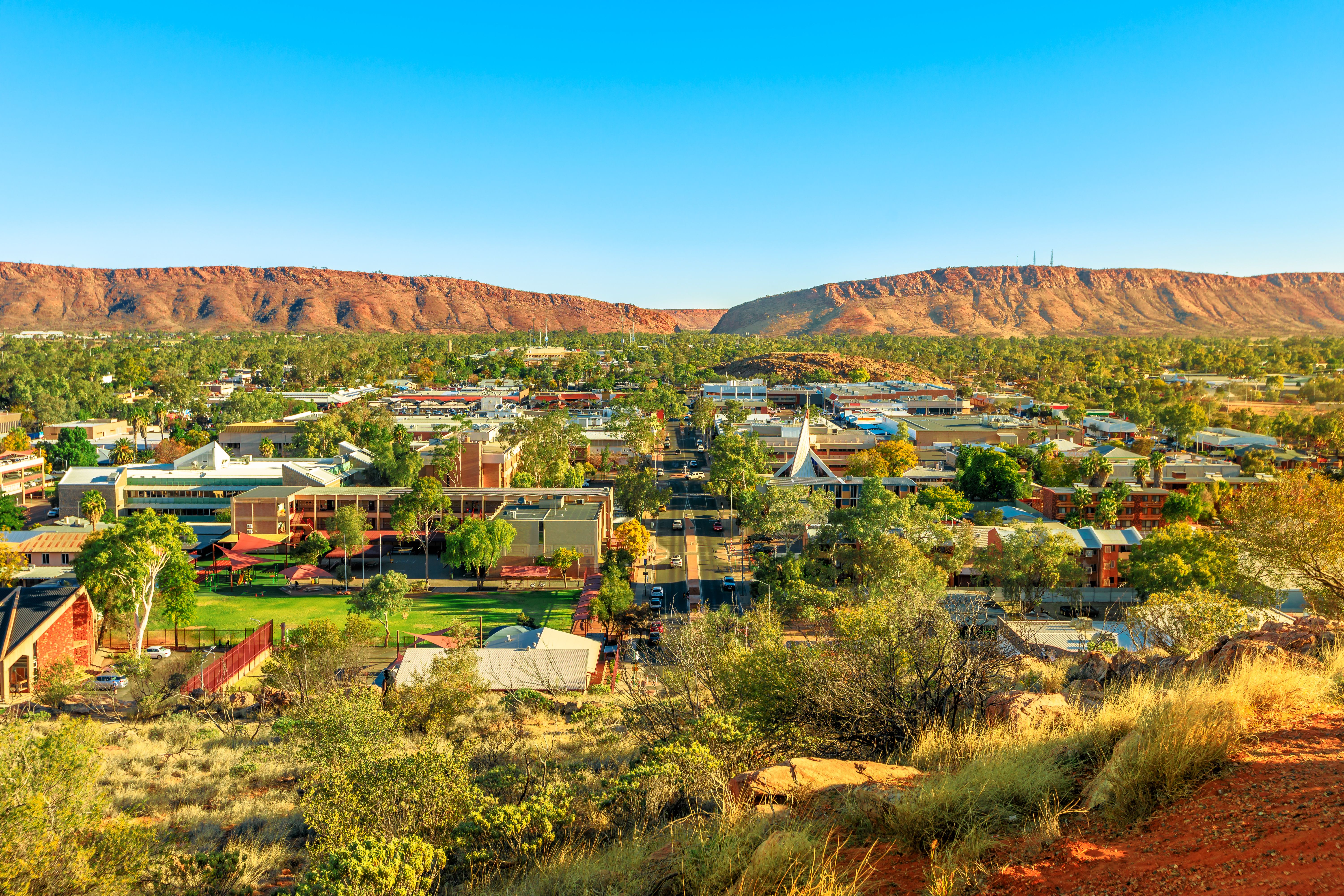 Aerial view of Alice Springs skyline in Australia from Anzac Hill Memorial lookout with main buildings of Alice Springs city downtown. Red Centre desert with Macdonnell ranges of Northern Territory