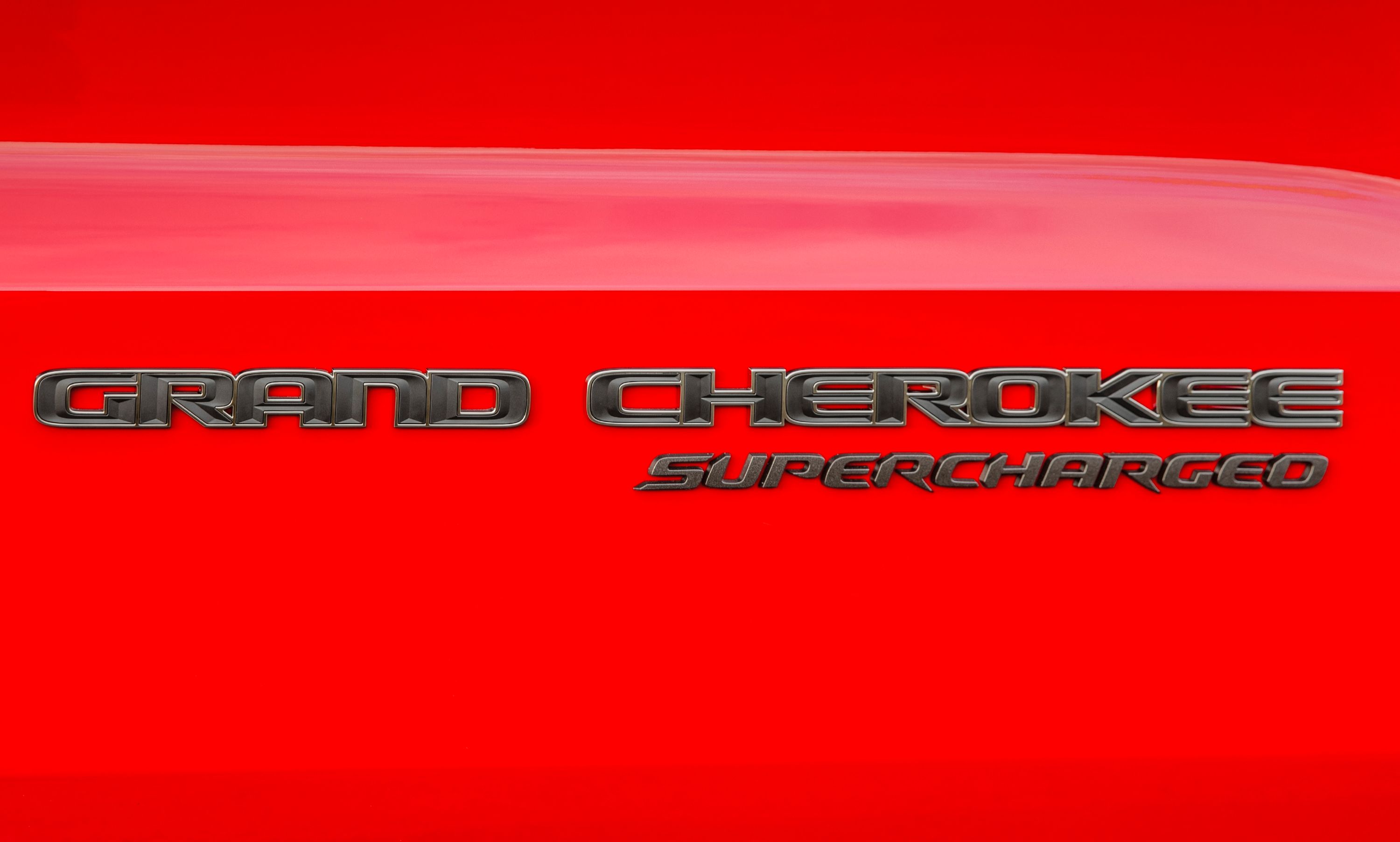 A Grand Cherokee Supercharged badge on a red vehicle