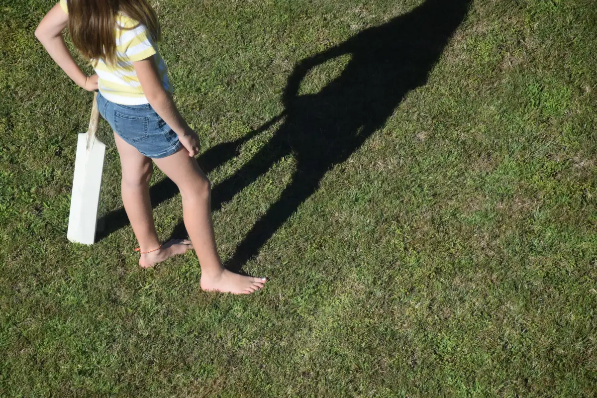a girl with a cricket bat on a grassy field