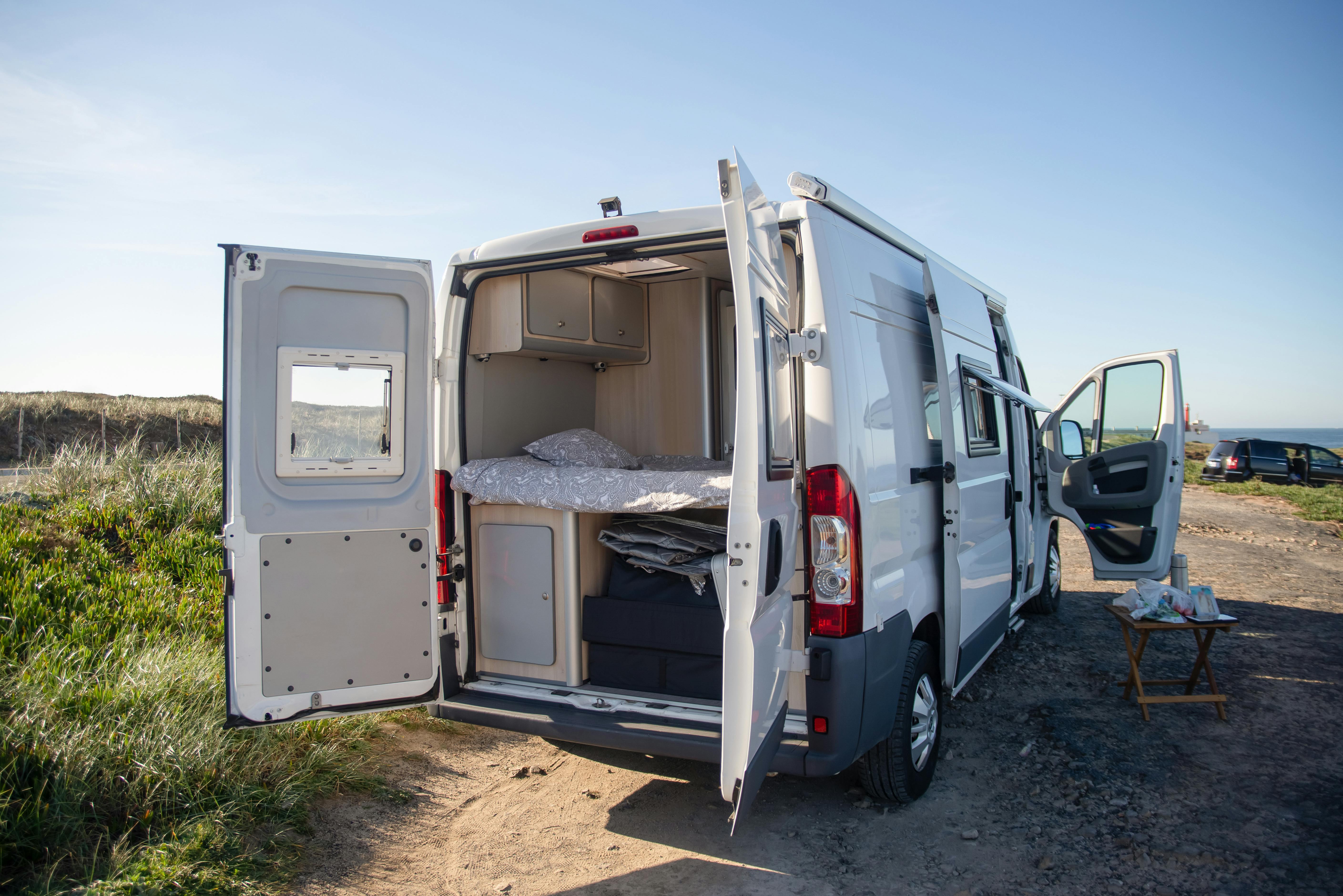 Back of a campervan open, showing bedding