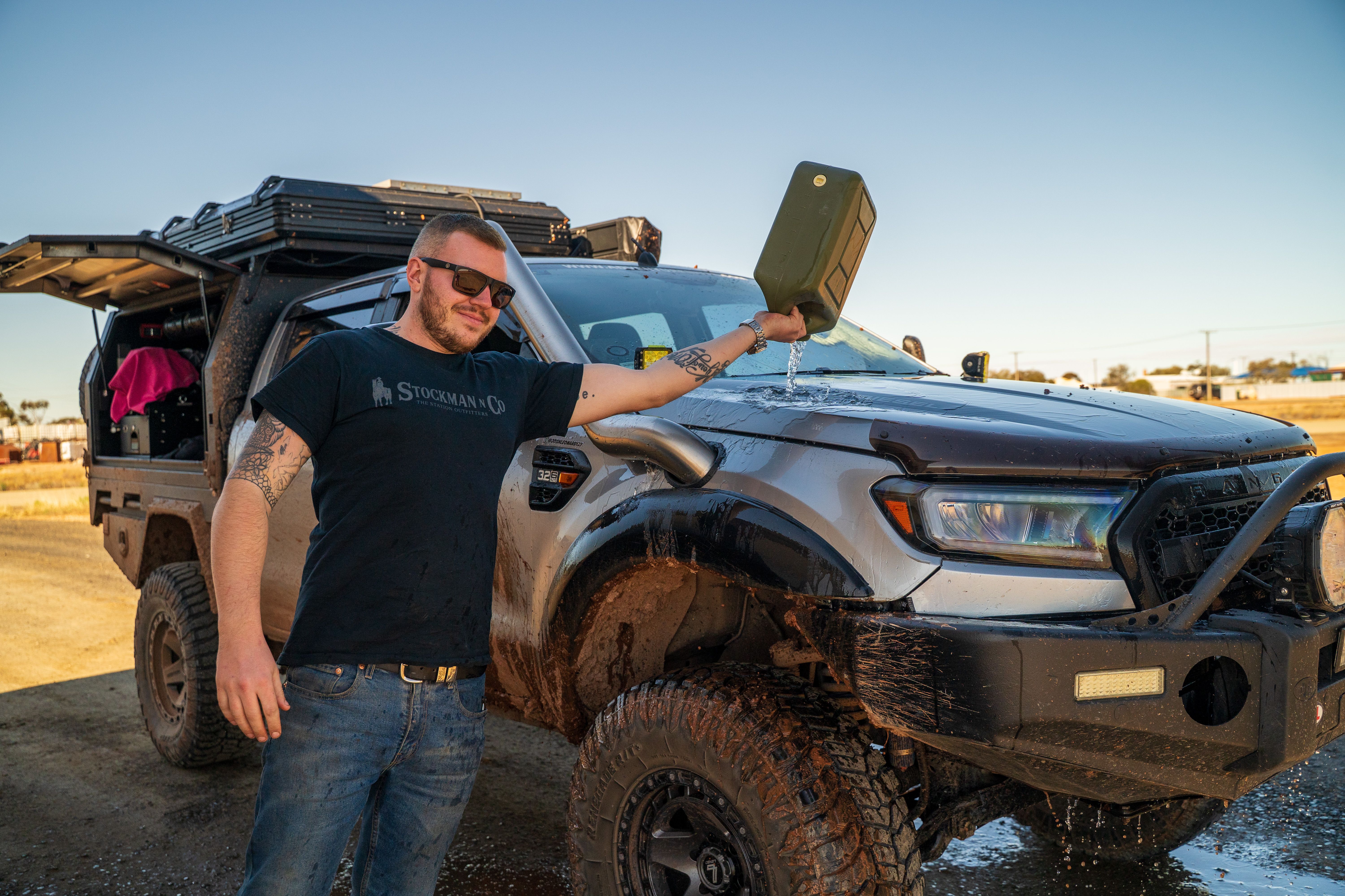Josh Leonard tipping out a jerry can of water over his 4X4 Ford Ranger ute