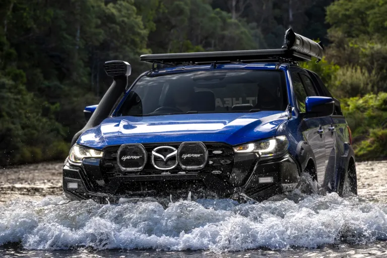 A blue 2025 Mazda BT-50 driving through water