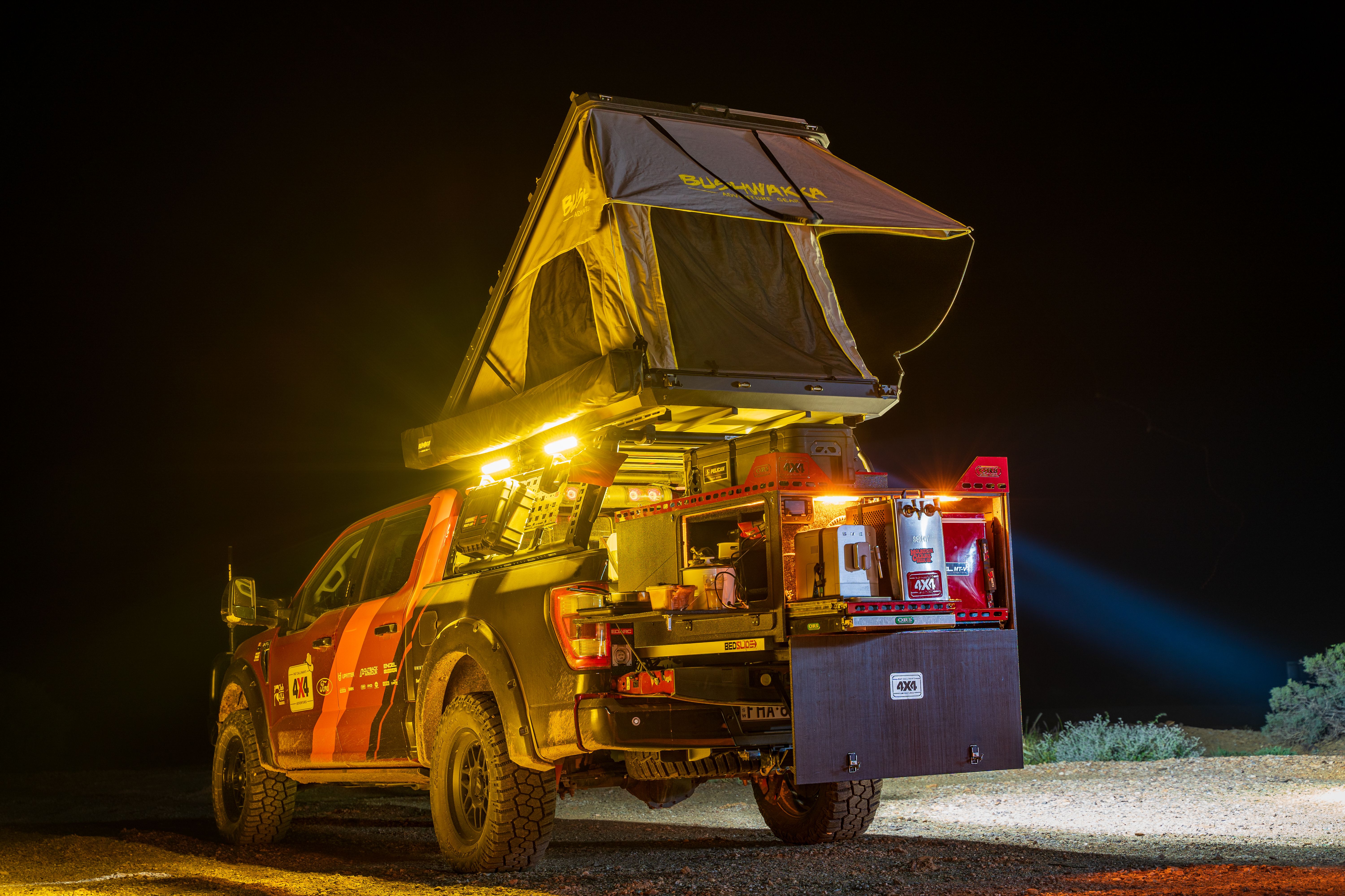 A 4X4's canopy open with lights, a fridge and other accessories