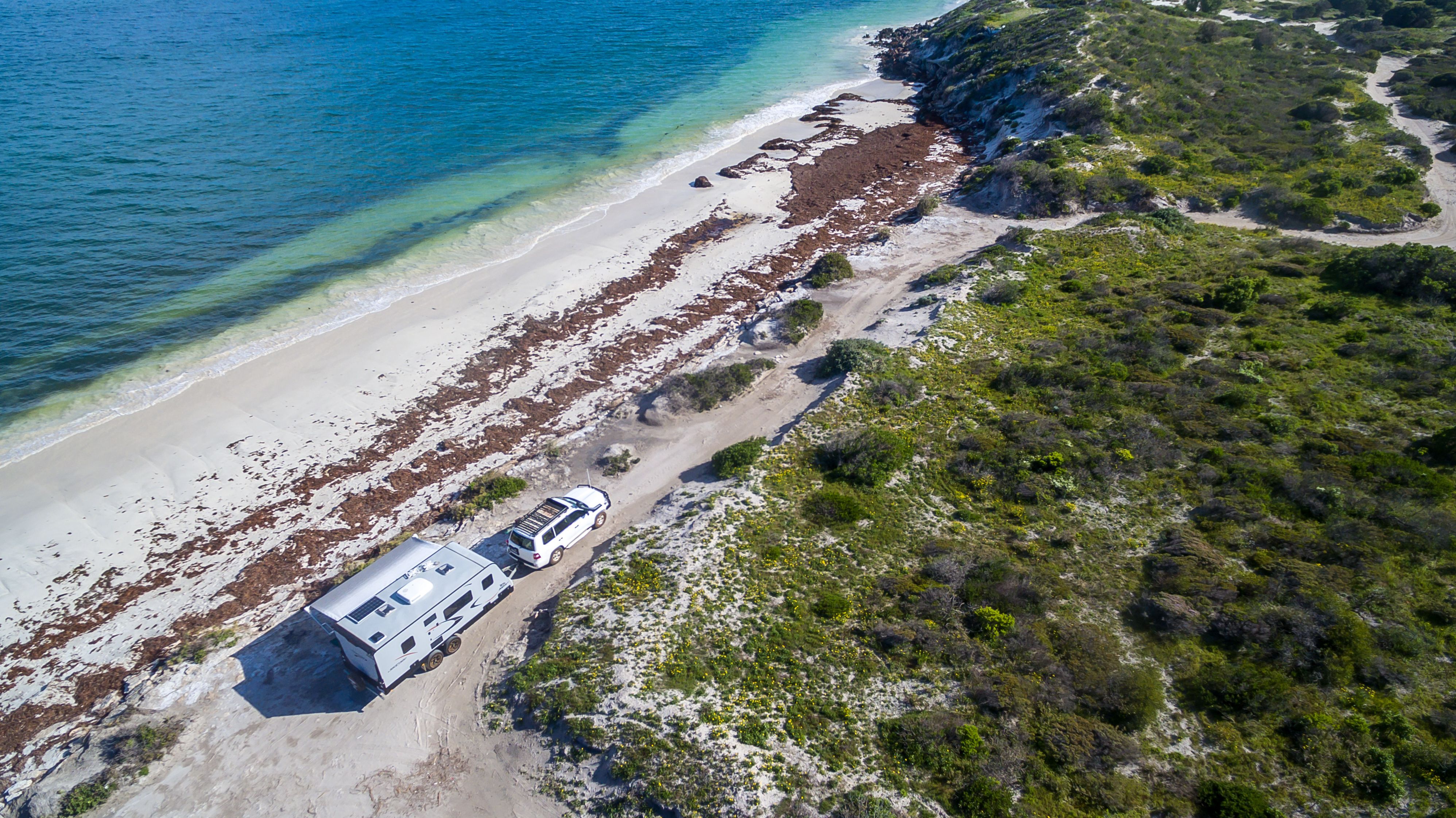 A caravan being towed along a sandy coastal trail