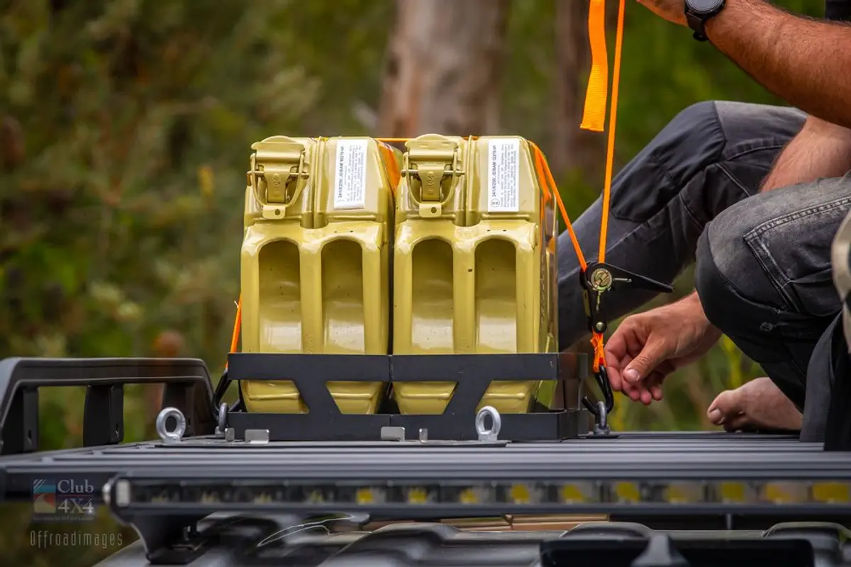 person tying down jerry can on roof rack