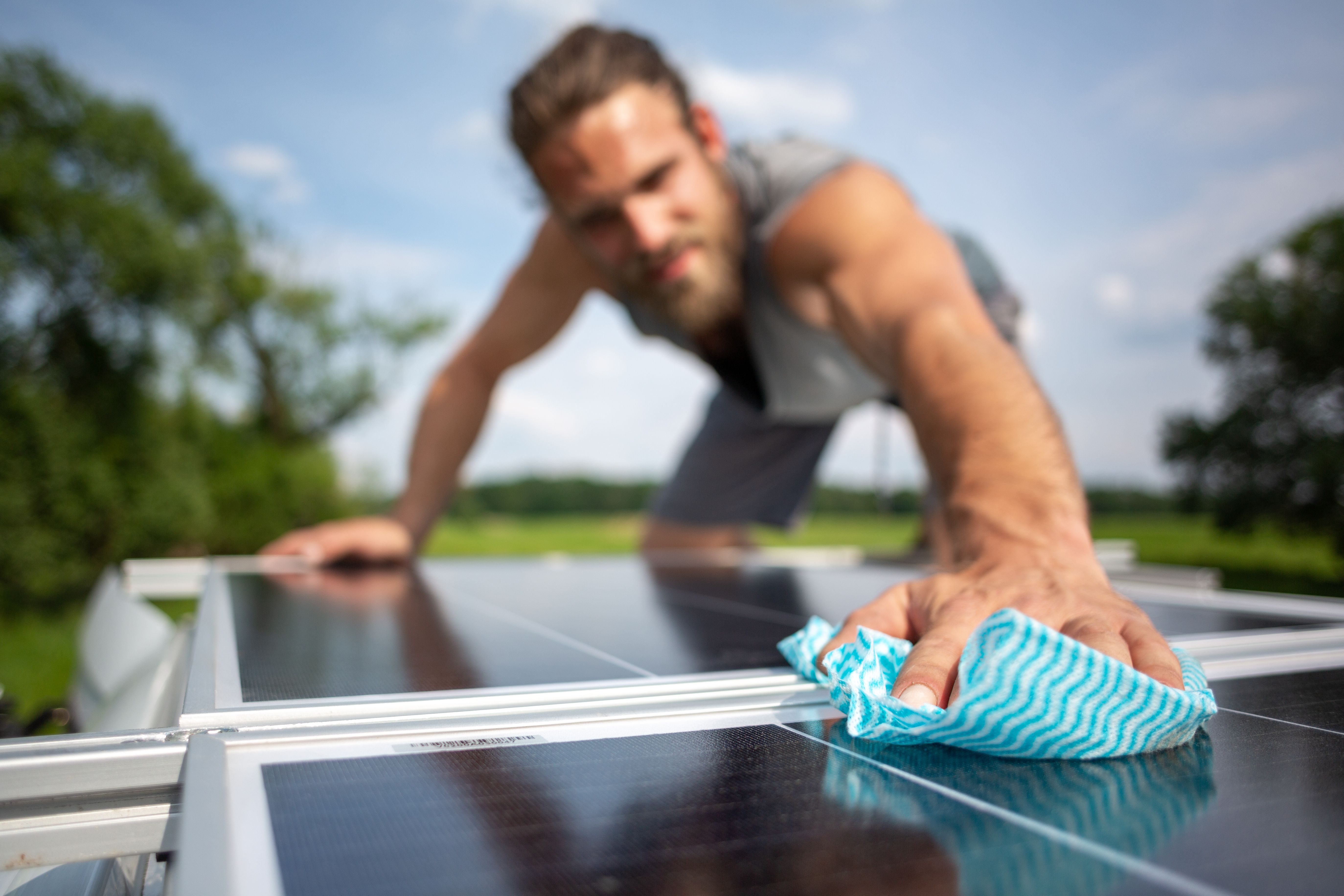 A man wiping down solar panels on the roof of a caravan