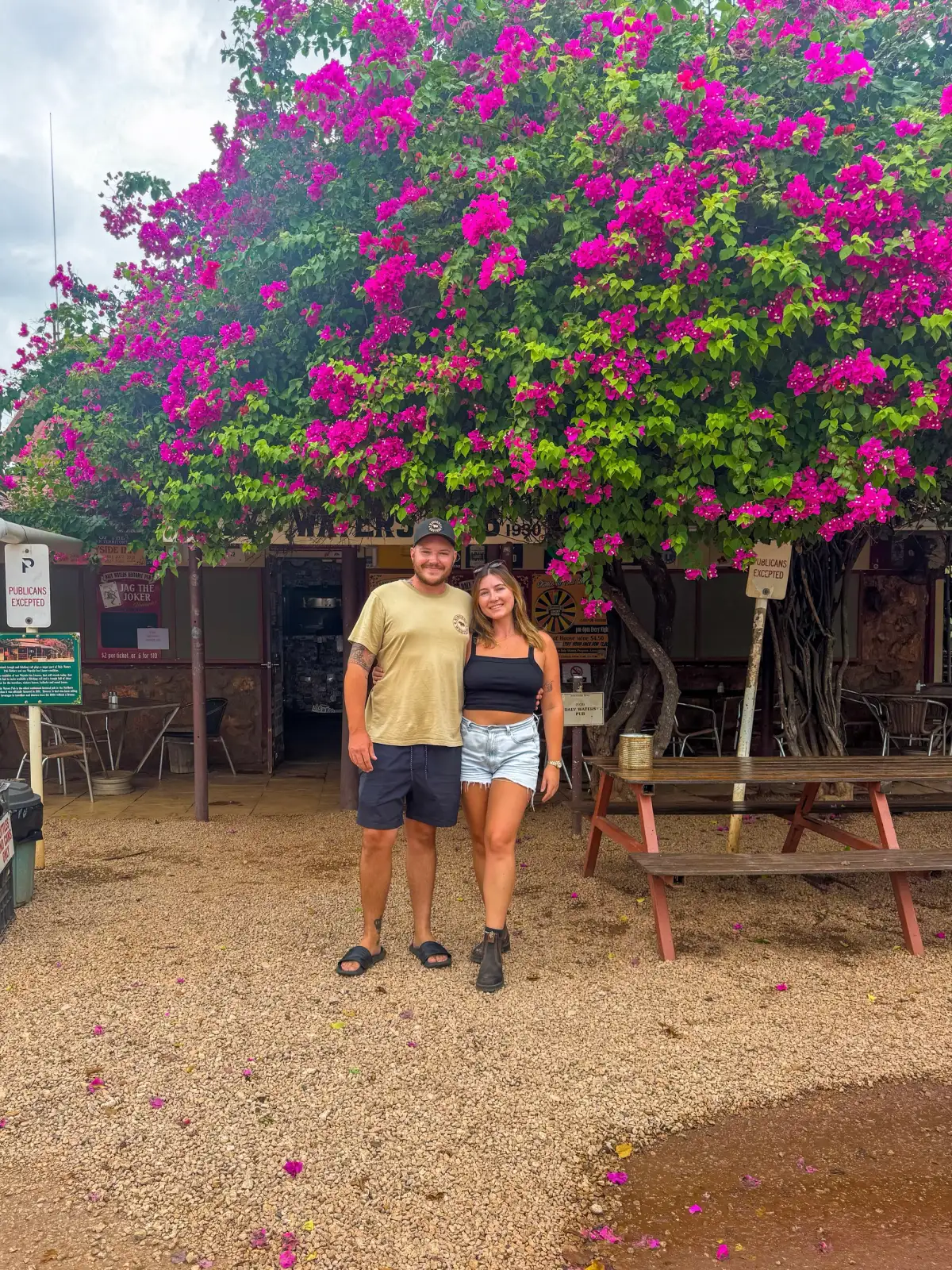 man and woman standing under a tree with purple flowers