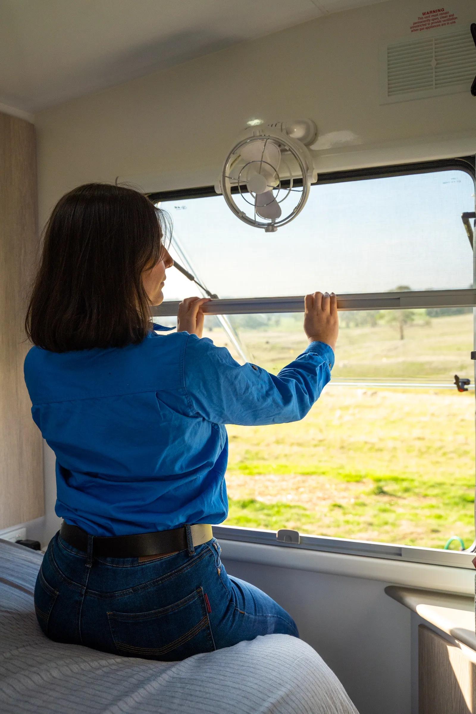 woman in a caravan closing a window