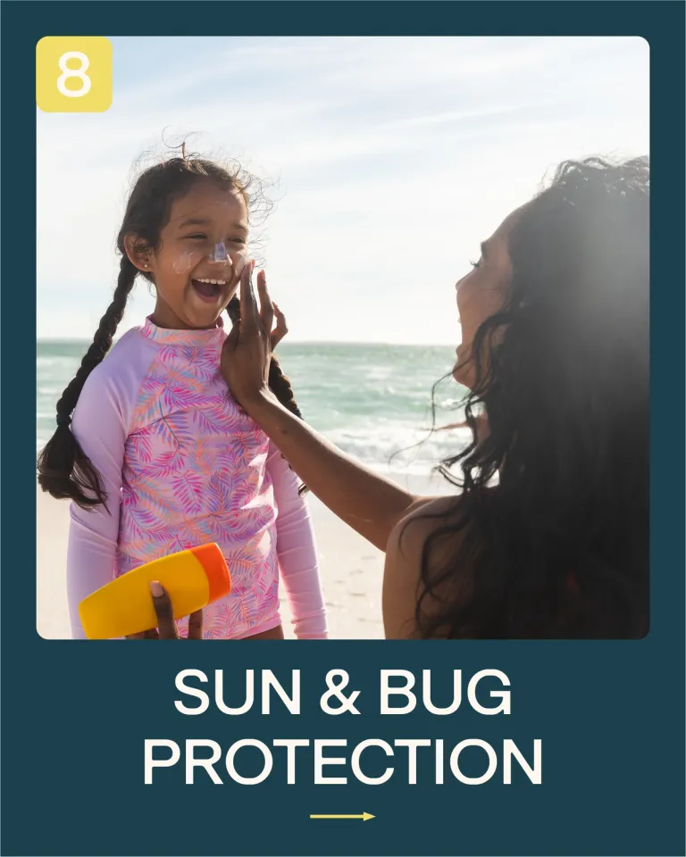 A woman puts sun cream on a child's face at the beach