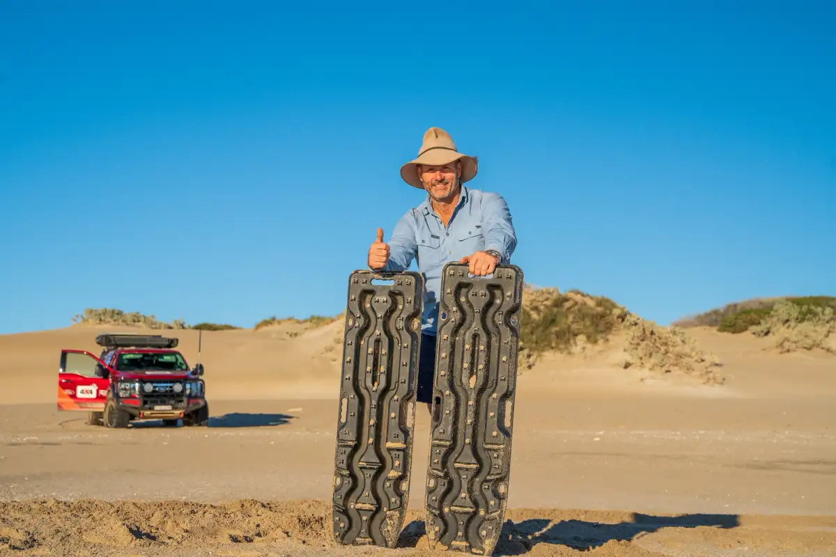 man with two traction aids with 4x4 in background in desert