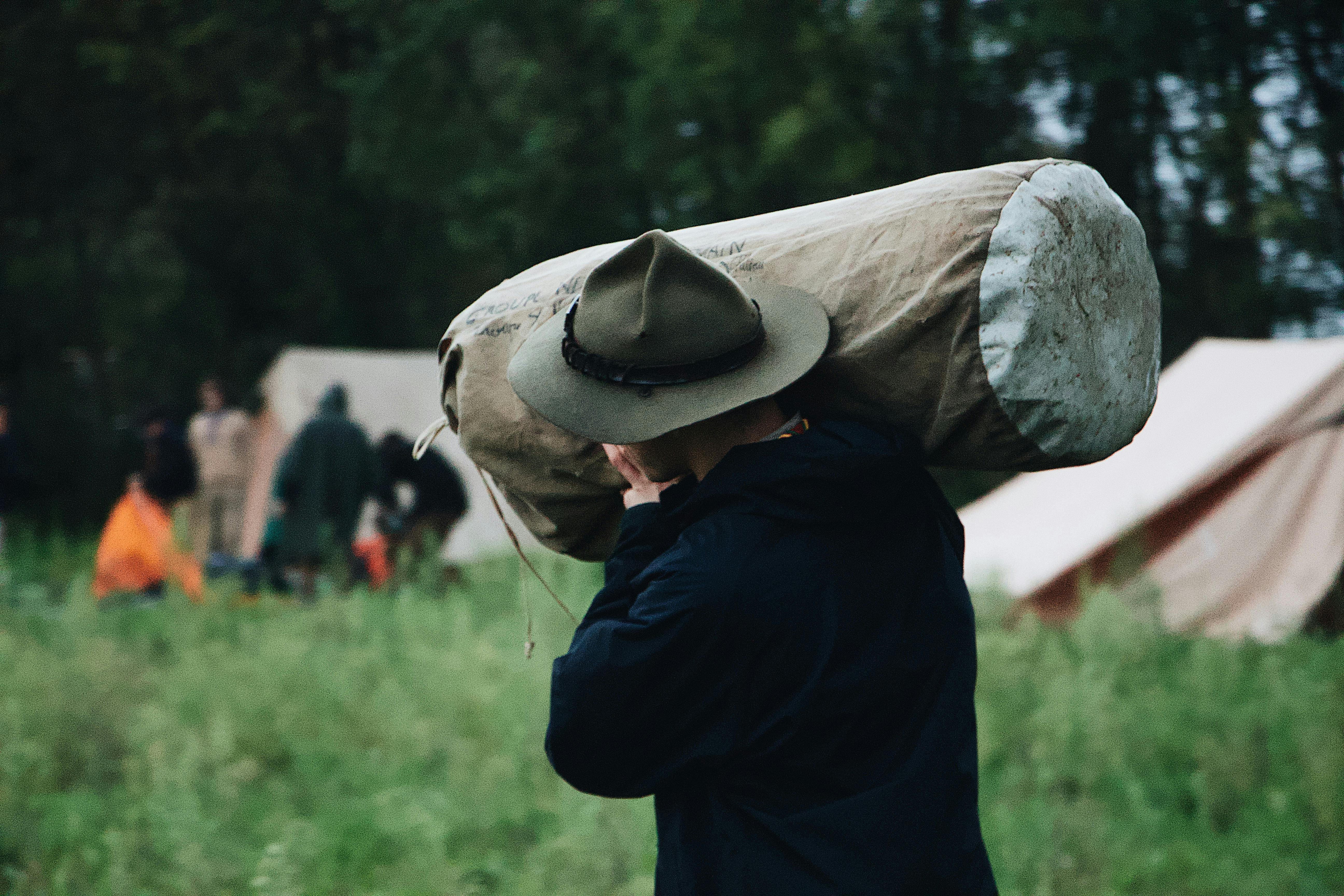 man carrying a swag at a campsite