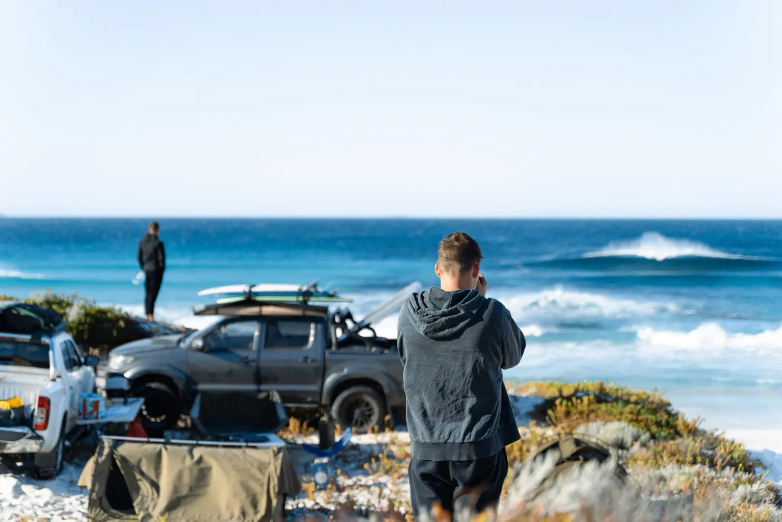 Some utes and people camping on the beach