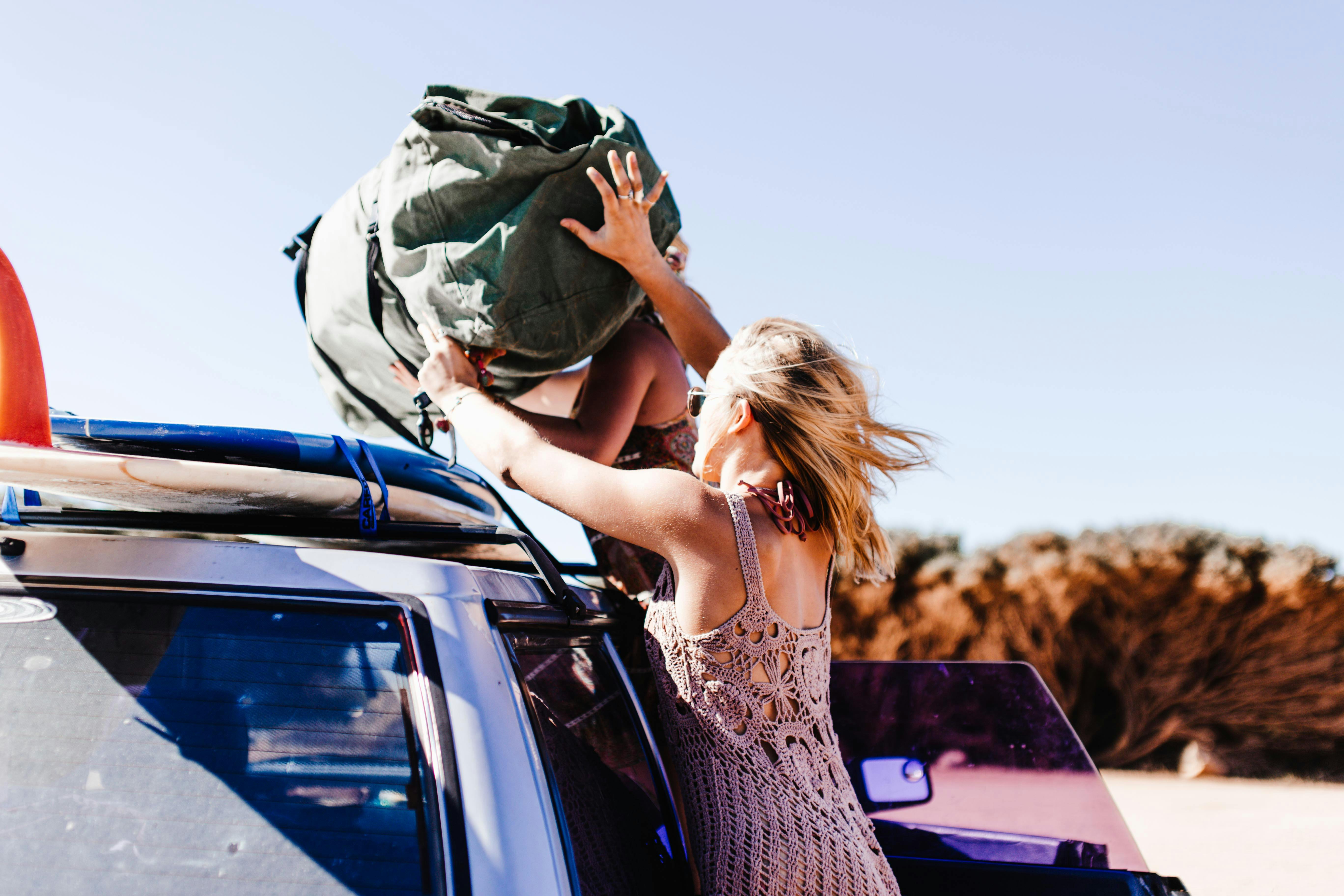 A woman putting a swag onto a 4WD's roof racks