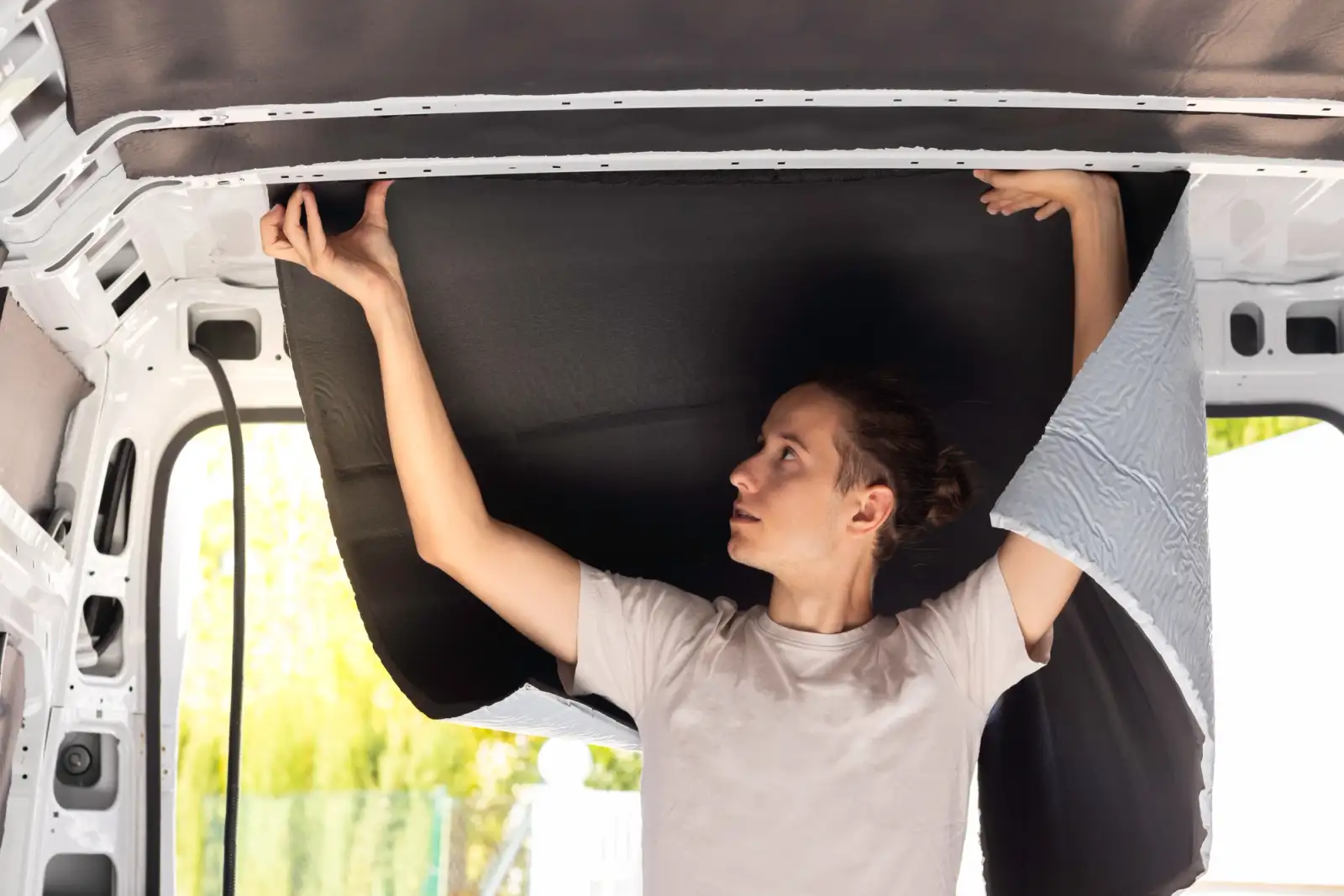 Woman installing insulation in the roof of a campervan