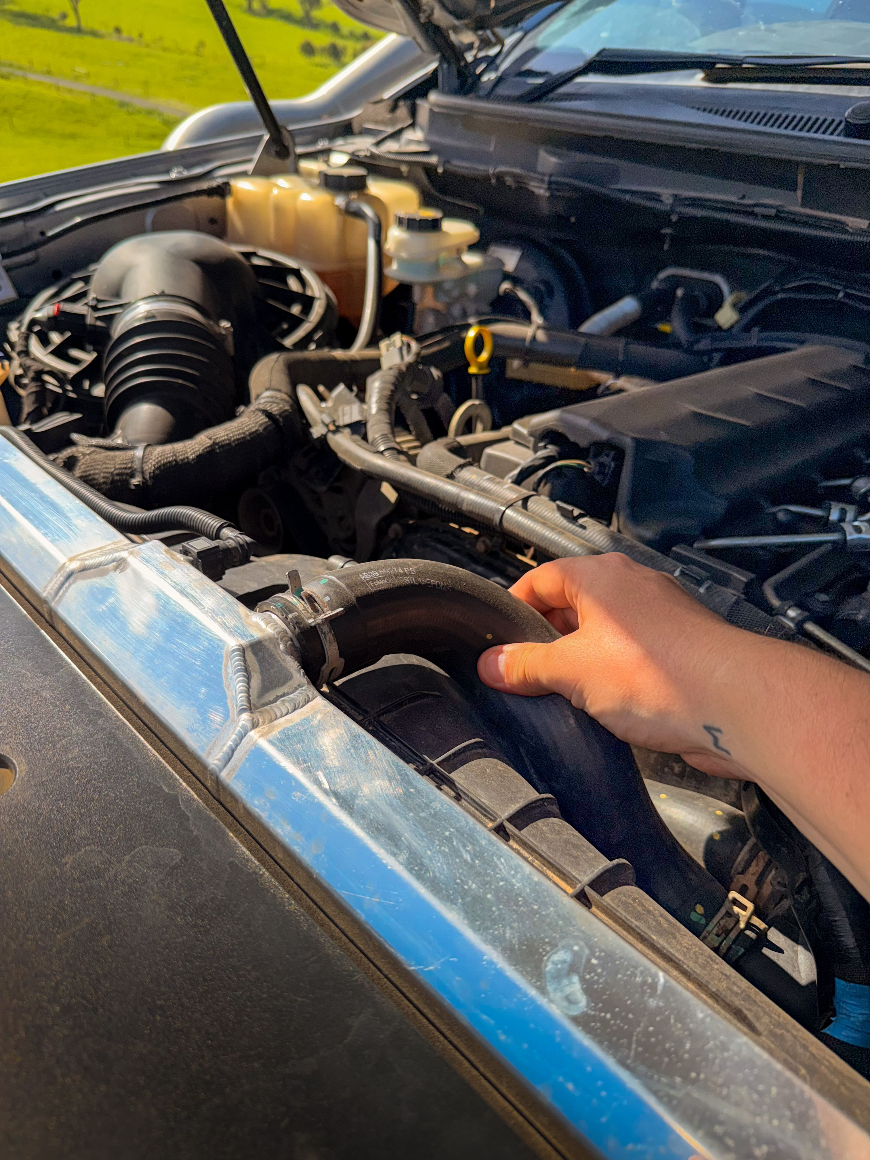 hand inside of a vehicle's engine bay