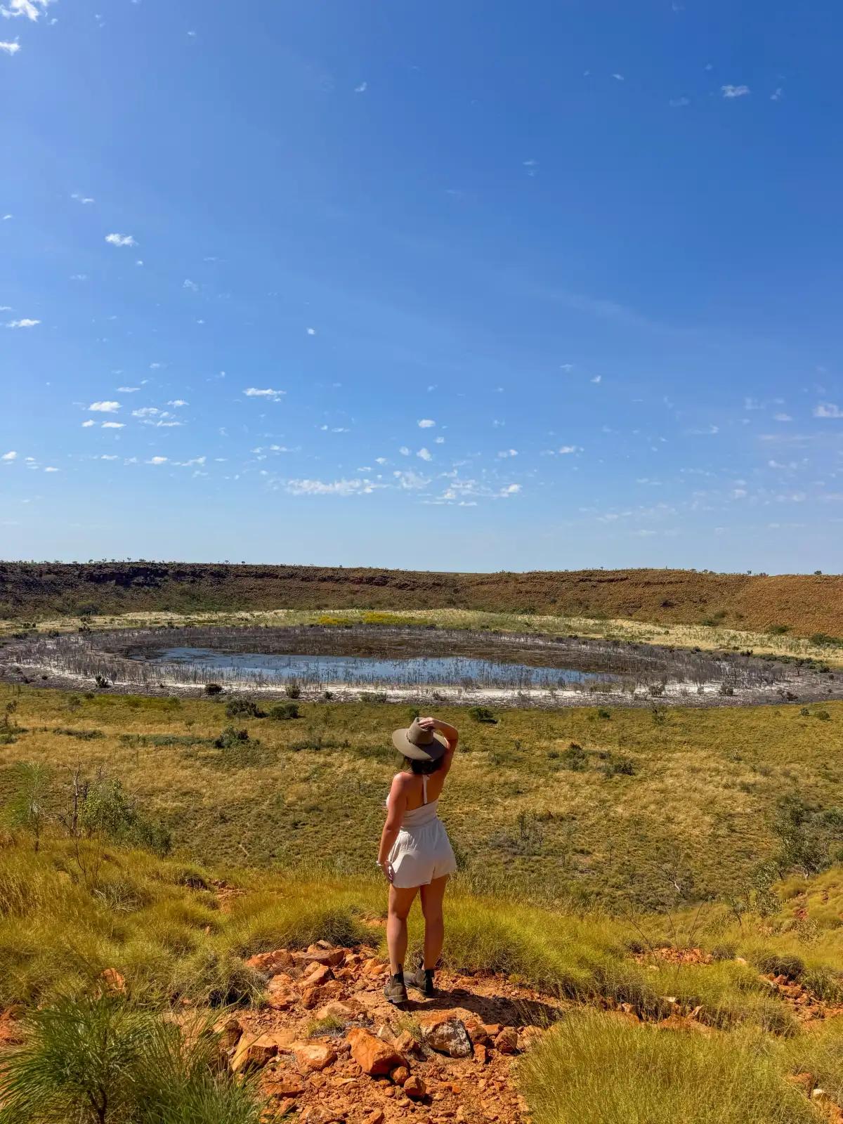 woman standing in field overlooking a waterhole