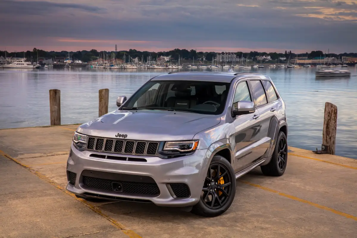 A silver grey Jeep Grand Cherokee Trackhawk near the water at sunset