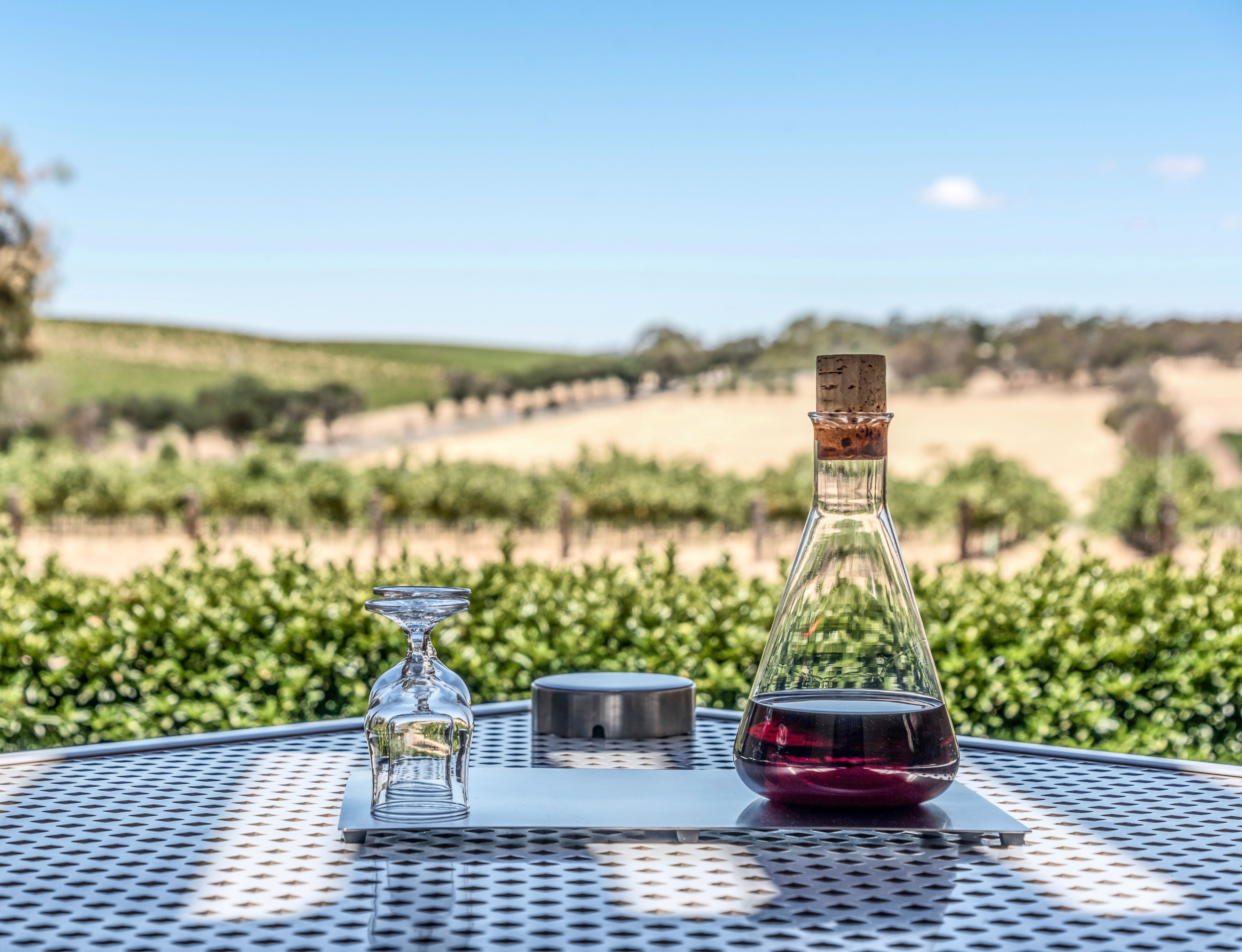 A bottle of tawny port, on a table in front of a vineyard in the Barossa Valley, Australia