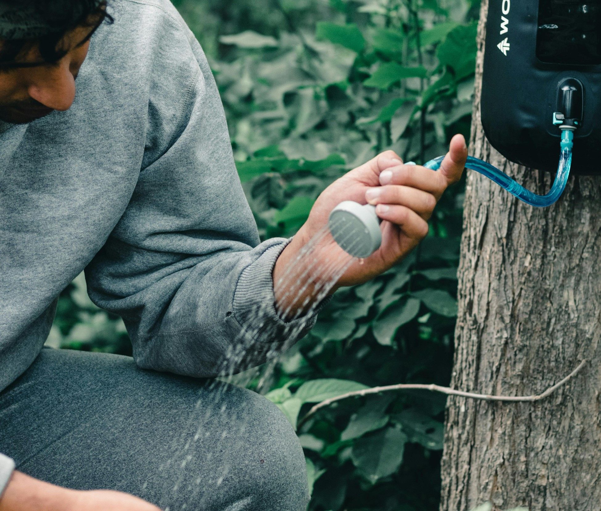A man operating a camp shower in a forest