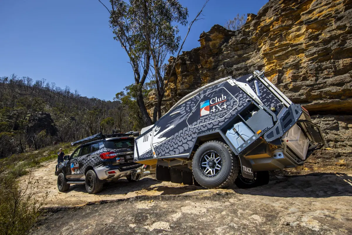Loaded touring 4WD towing a camper trailer on a rocky track