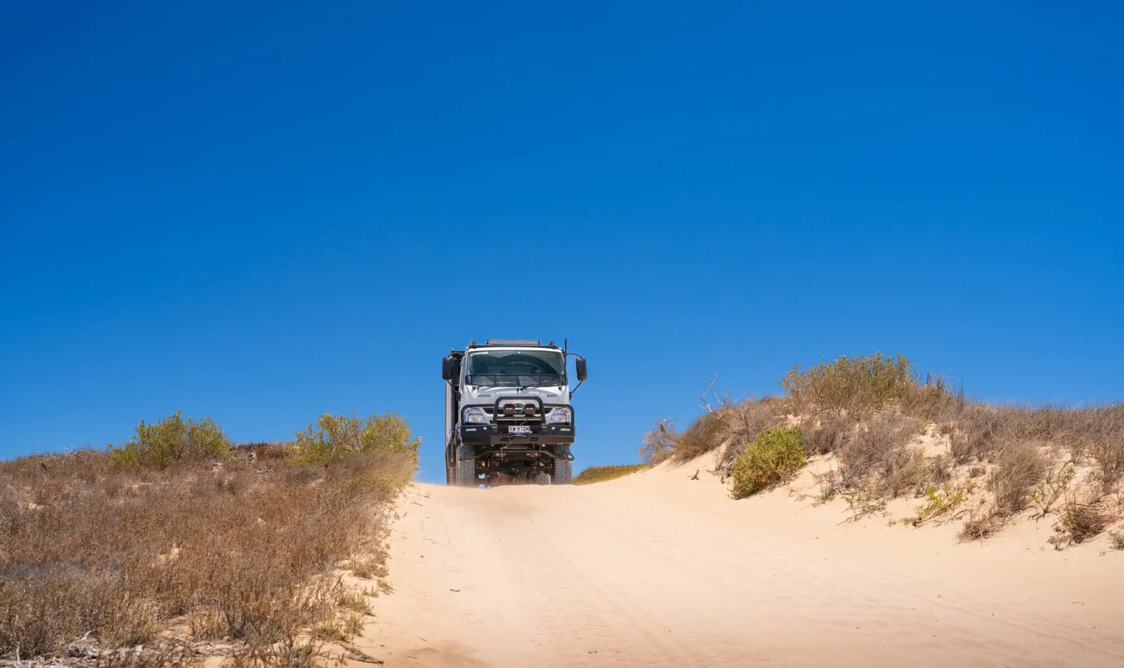 Hino 4WD Truck driving over sand dune